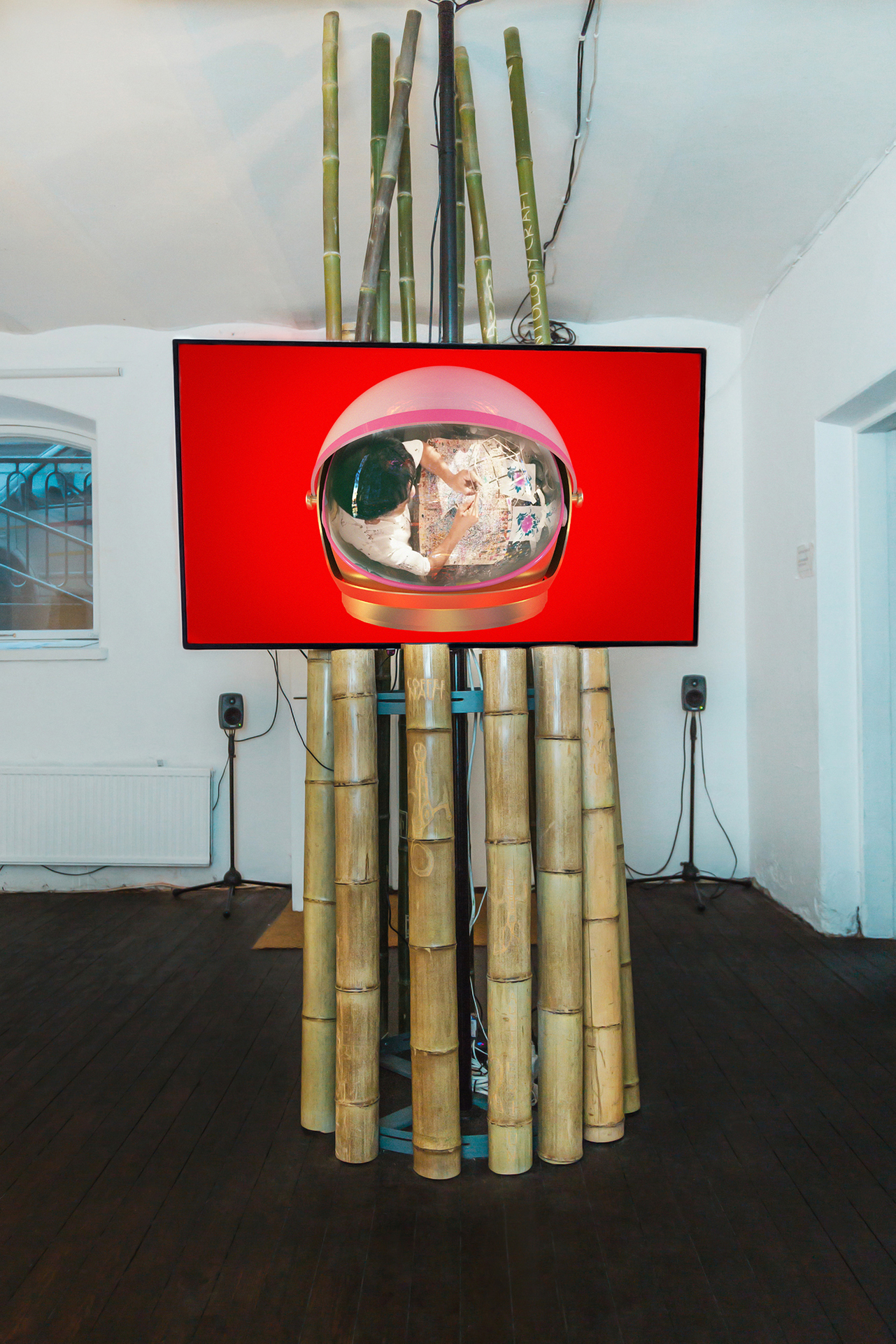 Monika Czyżyk, Geographies of a lonely Pole (I want to build a rocket), 2020, 4K UHD video, 82 min 48 s, color, stereo sound, 55” screen, auto pole mounting, bamboo poles with carved drawings by Torsten Zenas Burns mounted on steel hoop rack,  286 x 60 x 70 cm