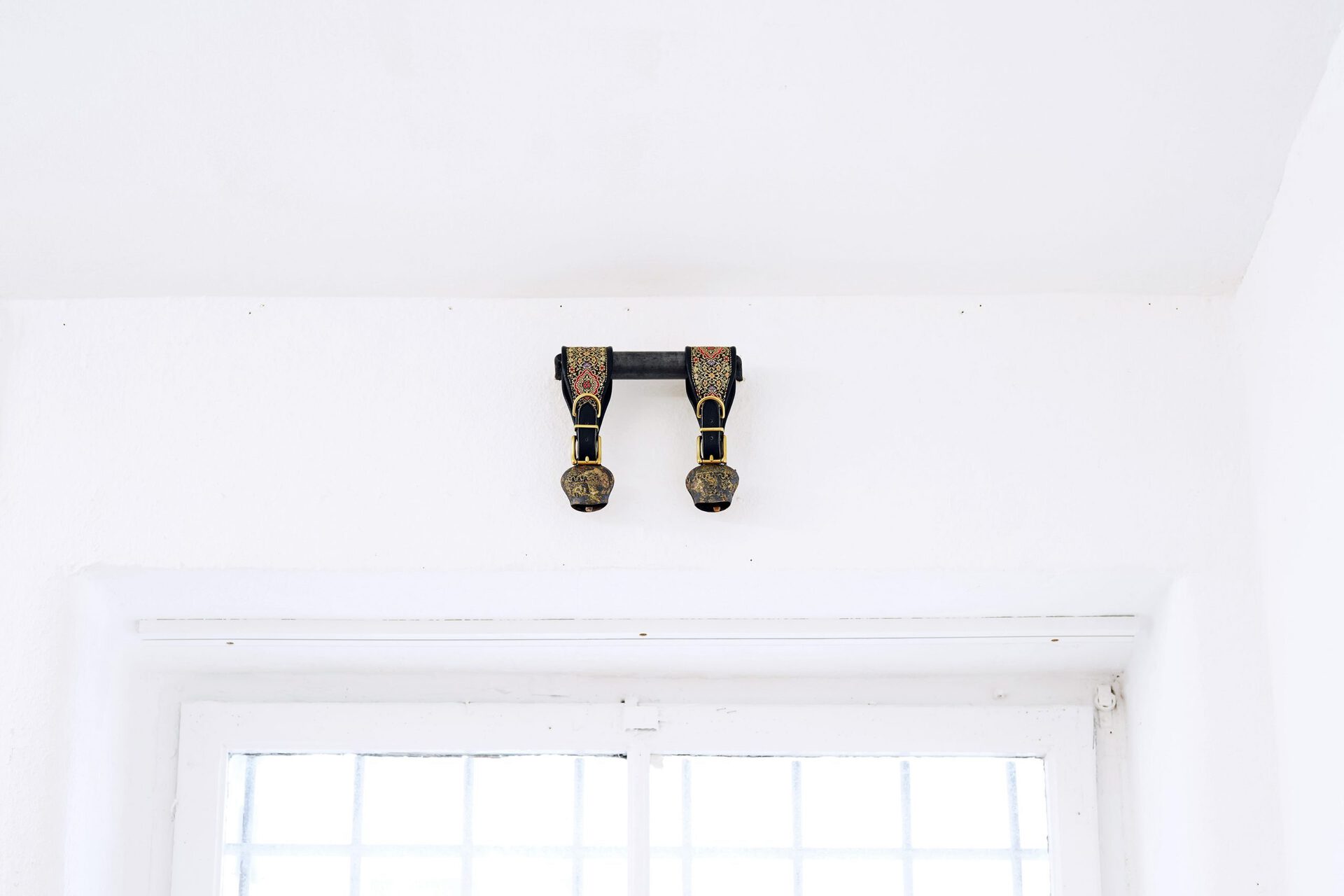 Eliza Ballesteros, DOMESTIC HECK II, 2019, antique goat bells with greyhound collars, brass, leather, brocade, iron hooks, 20 x 20 x 5 cm