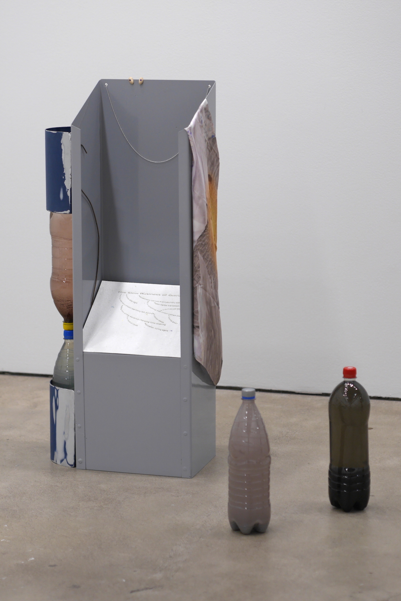 Stand byes and farewells (Neck-head sharpness of the day) 2020, powder-coated steel, laser engraved handmade paper, digital printed silk scarf, pistachio shells, chain, steel, aluminum, candies, waste bins, bottles filled with paper-pulp water