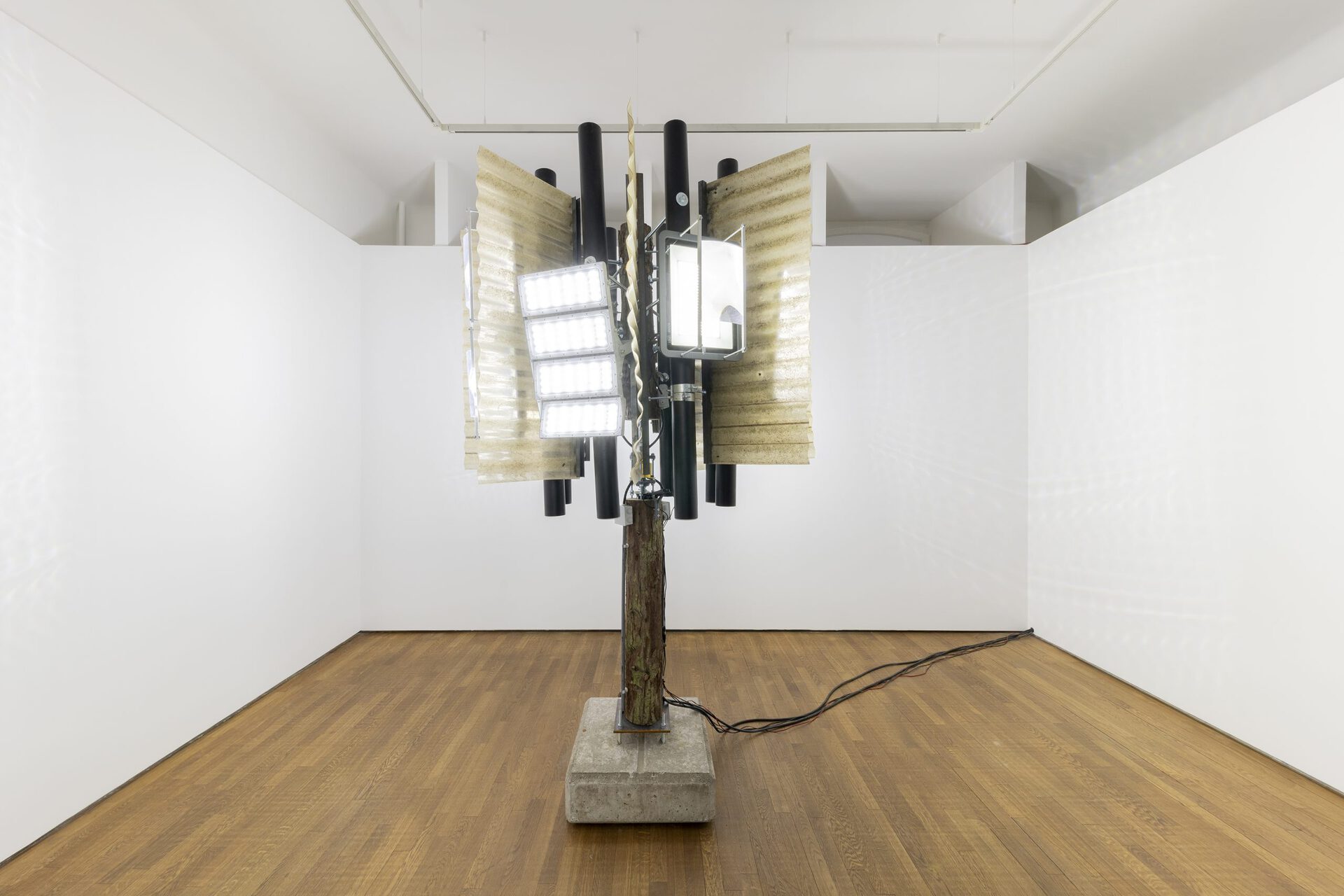 Arnaud Eubelen, No Man’s Land (rotating illuminated piece) 150X150X300 - 2020 Tree trunk - Corrugated sheets - threaded rod - led spotlight - steel - concrete - fresnel lens - electric motor - rotating collector - amplifier - vibration speakers - microphone
