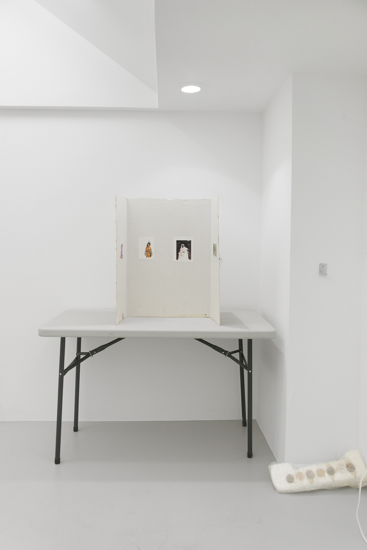 Justin Chance, Low-Life, 2021, Polyurethane, masking tape, color prints, cut paper, drywall tape, cross-stitch, project display board, folding table, holographic sticker, Dimensions variable.