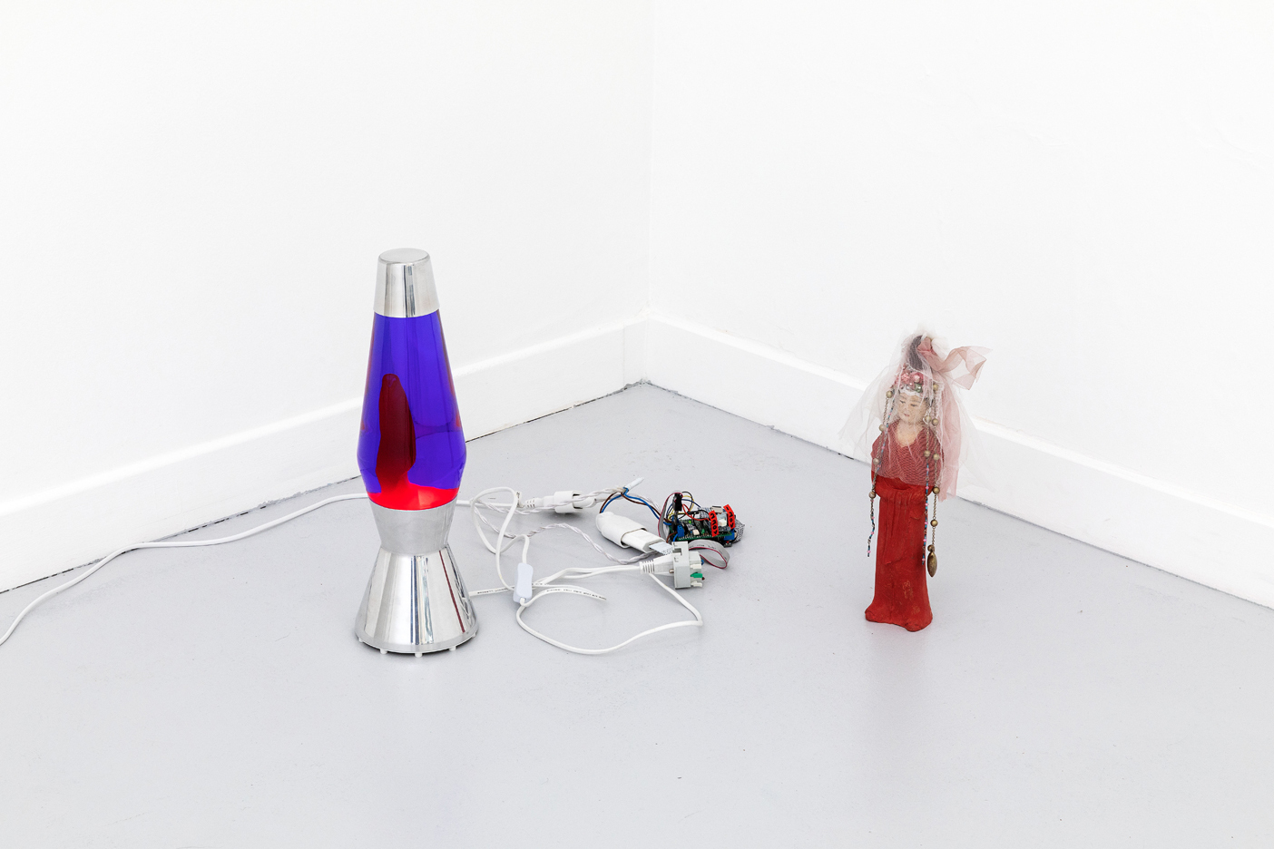 ici Wu, Go with the flow (make the world easier to understand, not complex to hide things), 2018 - 2021, Mathmos lava lamp,     	       arduino, electronic board, light data of film Tempting Heart (1999), cardboard, clay figurine of a woman, fabrics of dolls, neck-  	       lace, dimensions variable