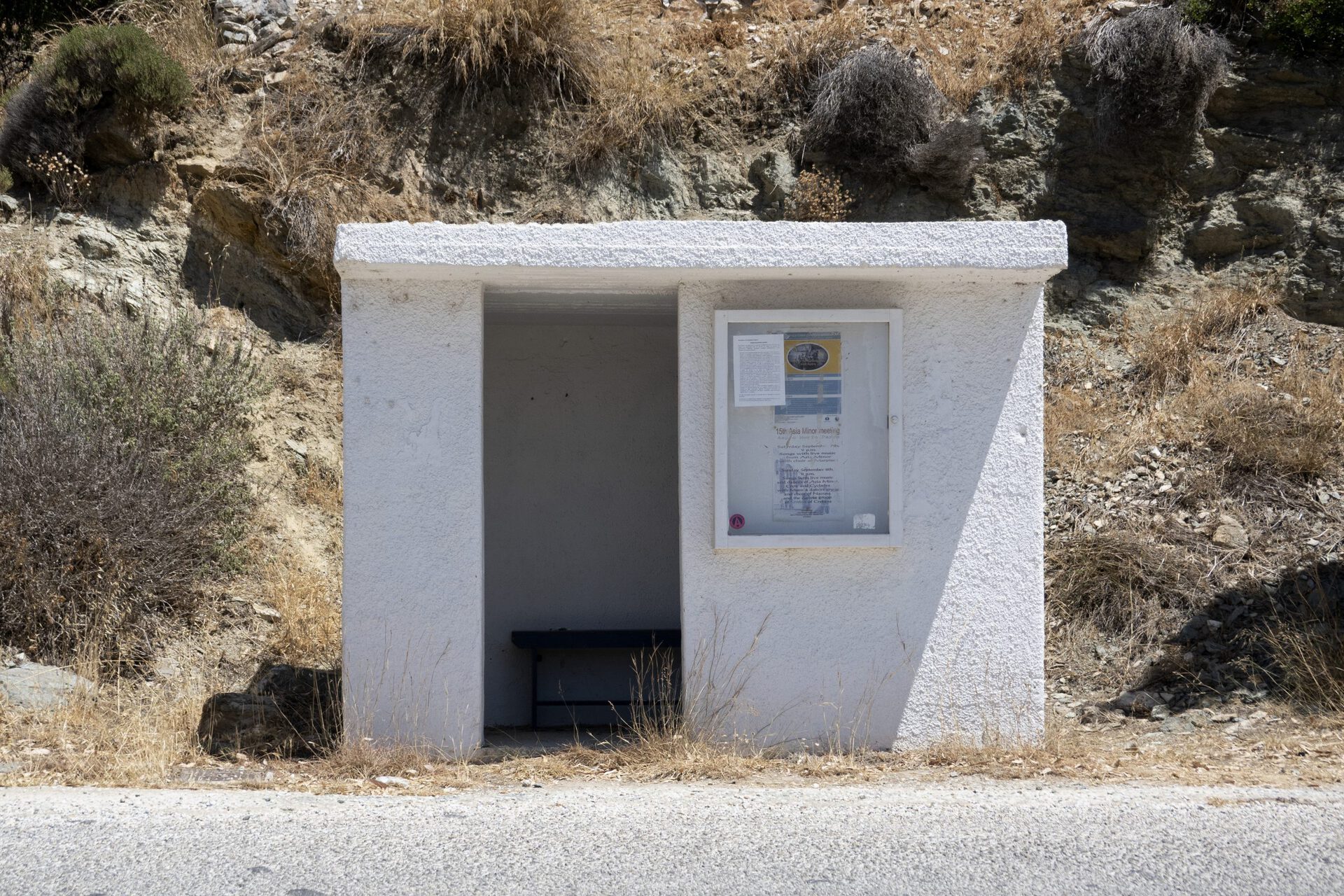 Ishai Shapira Kalter, "First Stop: Aspro Chorio", 2021. Installation view. After "Paradise Point", from the spectacular viewpoints in Paros and after driving on a small bridge, on the way to the village of Aspro Chorio at an embossed bus stop which resembles a tiny solitary confinement cell with blue mailboxes and old magazines scattered on a bench, you will find a single crate / painting.