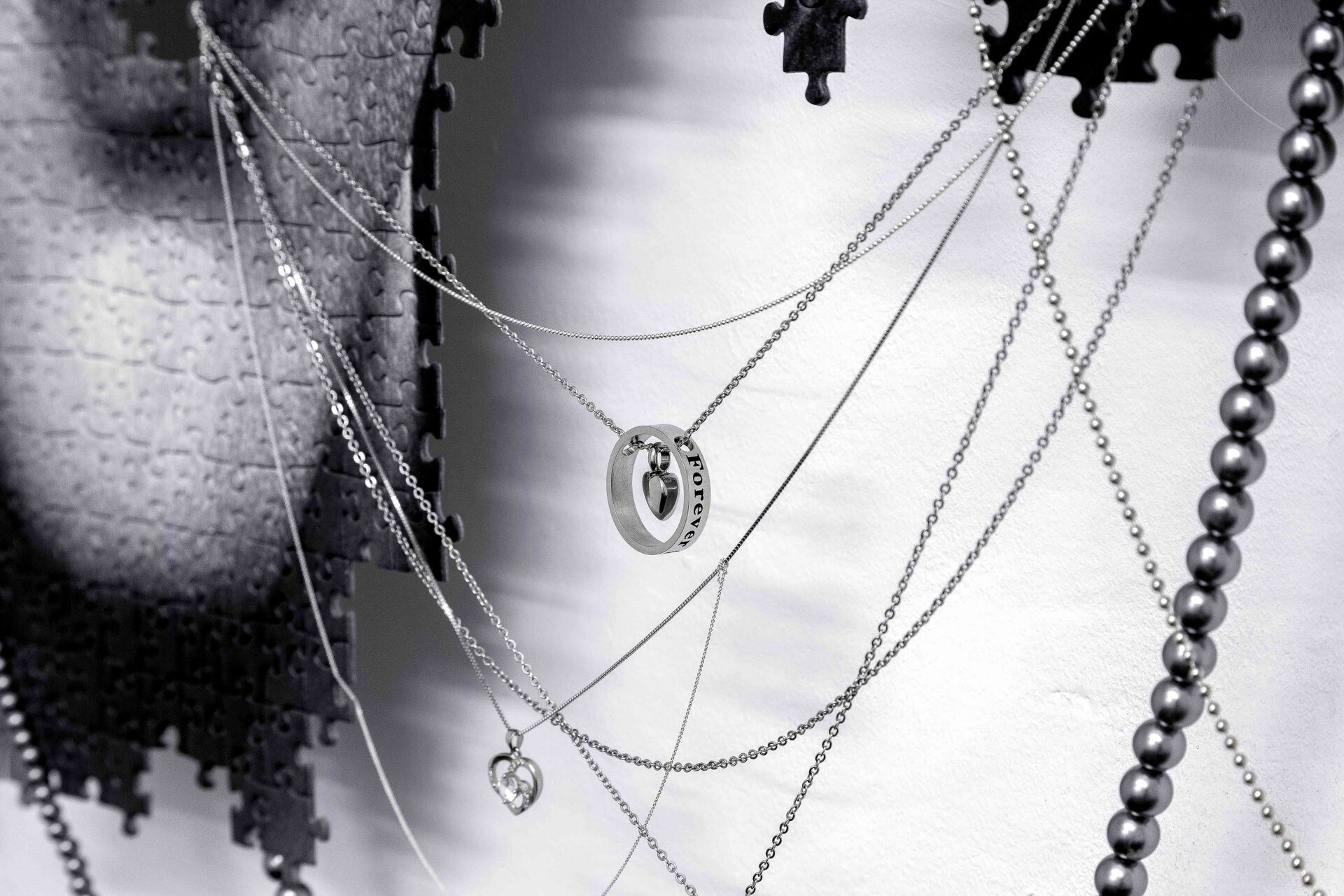Julian-Jakob Kneer, EROS / THANATOS (YOU DID IT, FOREVER YOUNG), 2021, Digital print on puzzle, silver and steel chains, engraved silver and steel lockets, plastic coated jewelry, aluminium construction, 105cm x 90cm x 7cm
