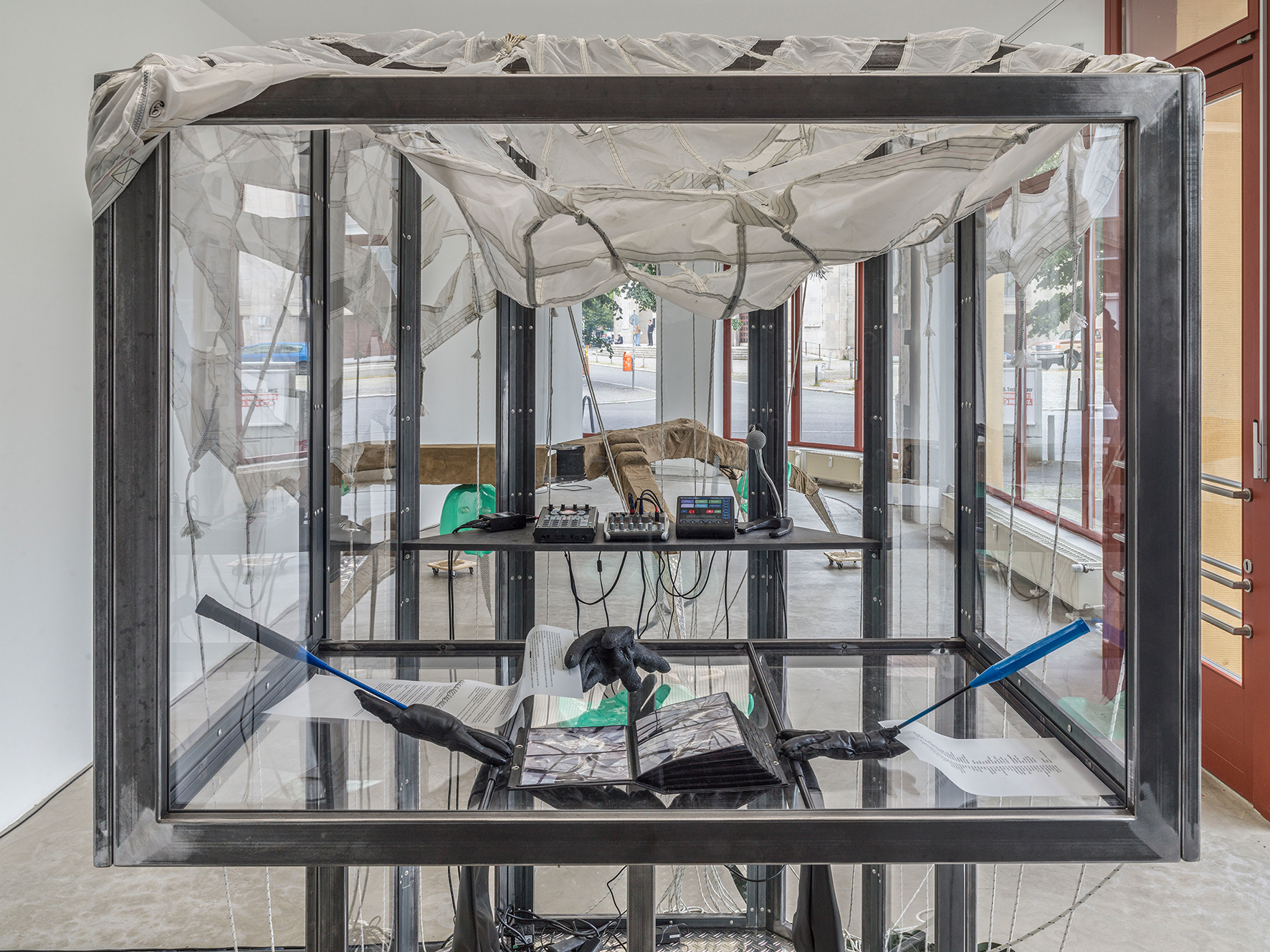 Mara Wohnhaas, “Rekommandeur I”, 2021, 2-parts, Cabin: Steel, chequer plate, polycarbonate, glass, MDF, parachute, mixing console, microphone, linear wave sampler, touch matrix mic stand-mount vocal effects processor, DJDI-box, lacquered plastic seat, lacquered rubber gloves, photo album, leather gloves with badminton racket and fishhooks, rubber gloves, texts on transparent paper, chain rings, 2 speakers, audio cable, sound 10 min (in collaboration with Simon Wallnöfer), 253 x 200 x 208,5 cm, Courtesy BQ, Berlin (Detail)