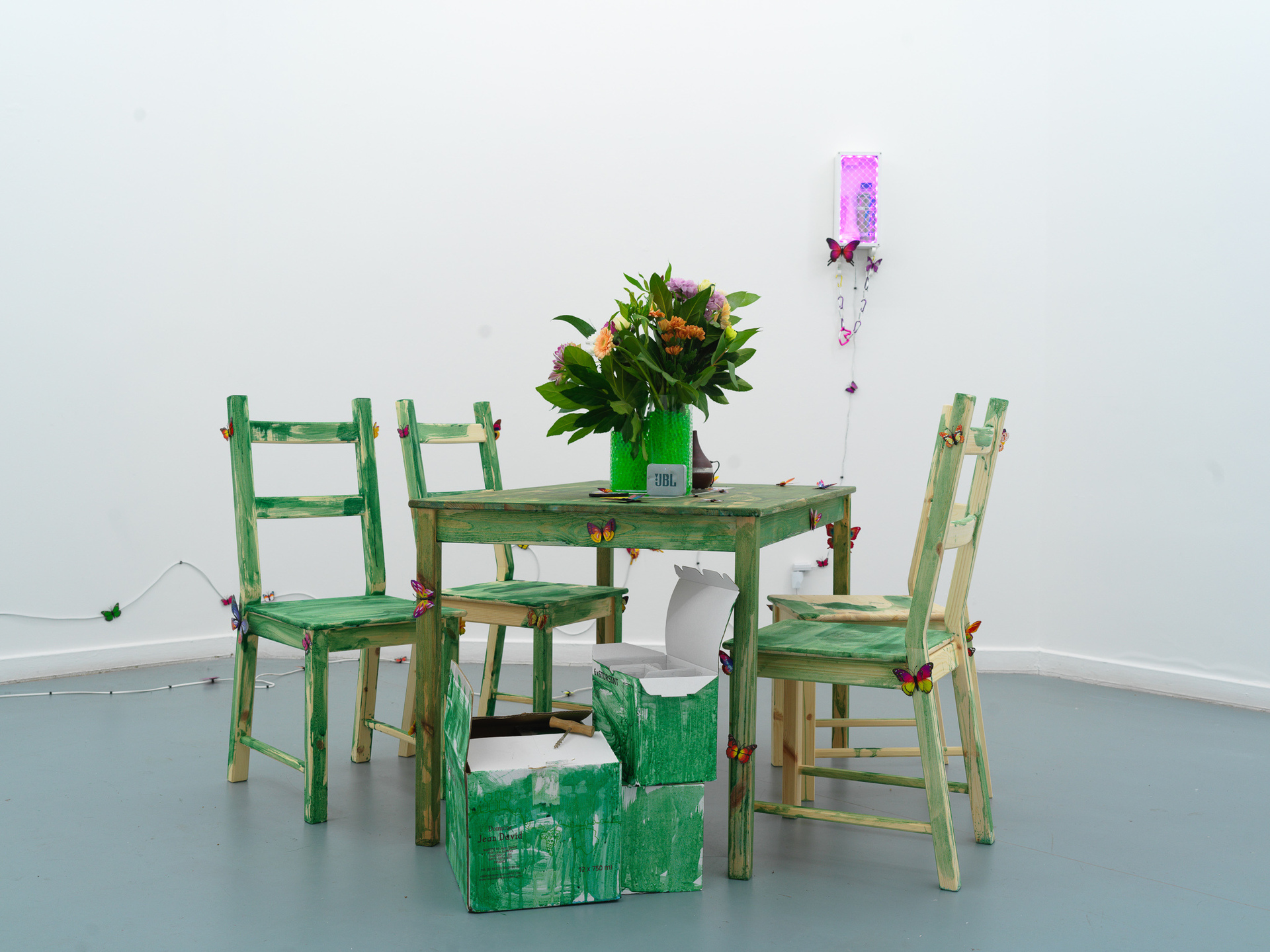 Artist: Theodor Nymark Title: The Mesh Year: 2021 Materials: IKEA IVAR dinner table set with chairs dyed with spirulina, aroma diffuser with Monster Energy Paradise, bluetooth speaker with custom soundtrack, custom box dyed with spirulina for natural wine, custom box dyed with spirulina for IKEA wine glasses, IKEA CYLINDER vases with water pearls and flowers from Aldi.