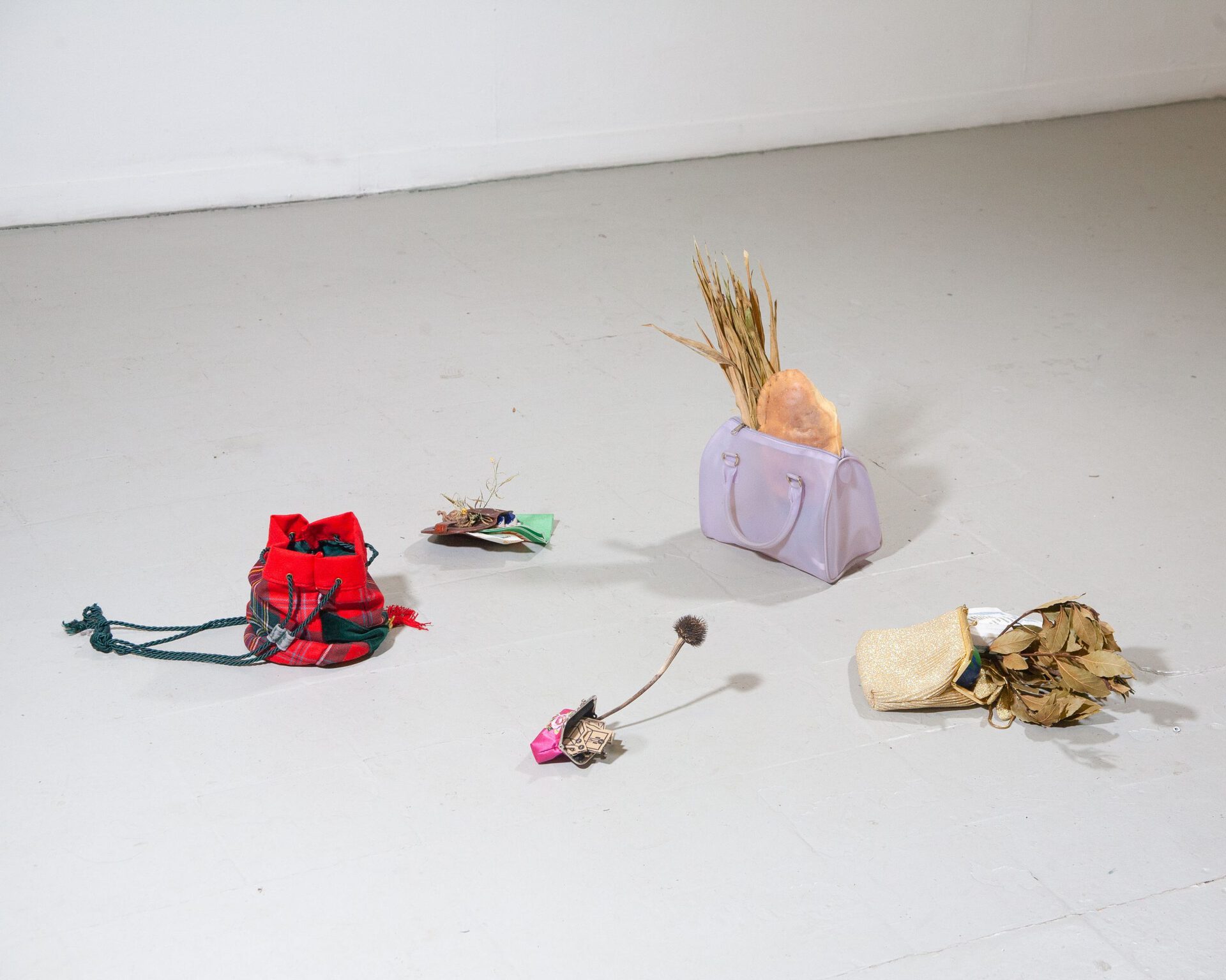 Daniele Formica, "harvest bags" , 2020/21, 3 purses, 2 wallets, crab head (cancer pagurus), Yucca leaves, stone, laurel branch, mixed shrubs, cardboard cut-outs, gloves, globe-shaped rubber stress-ball, paper napkin from Greek restaurant, ceramic house miniature, dry yam, silica gel bag, napkin, 10 cents.