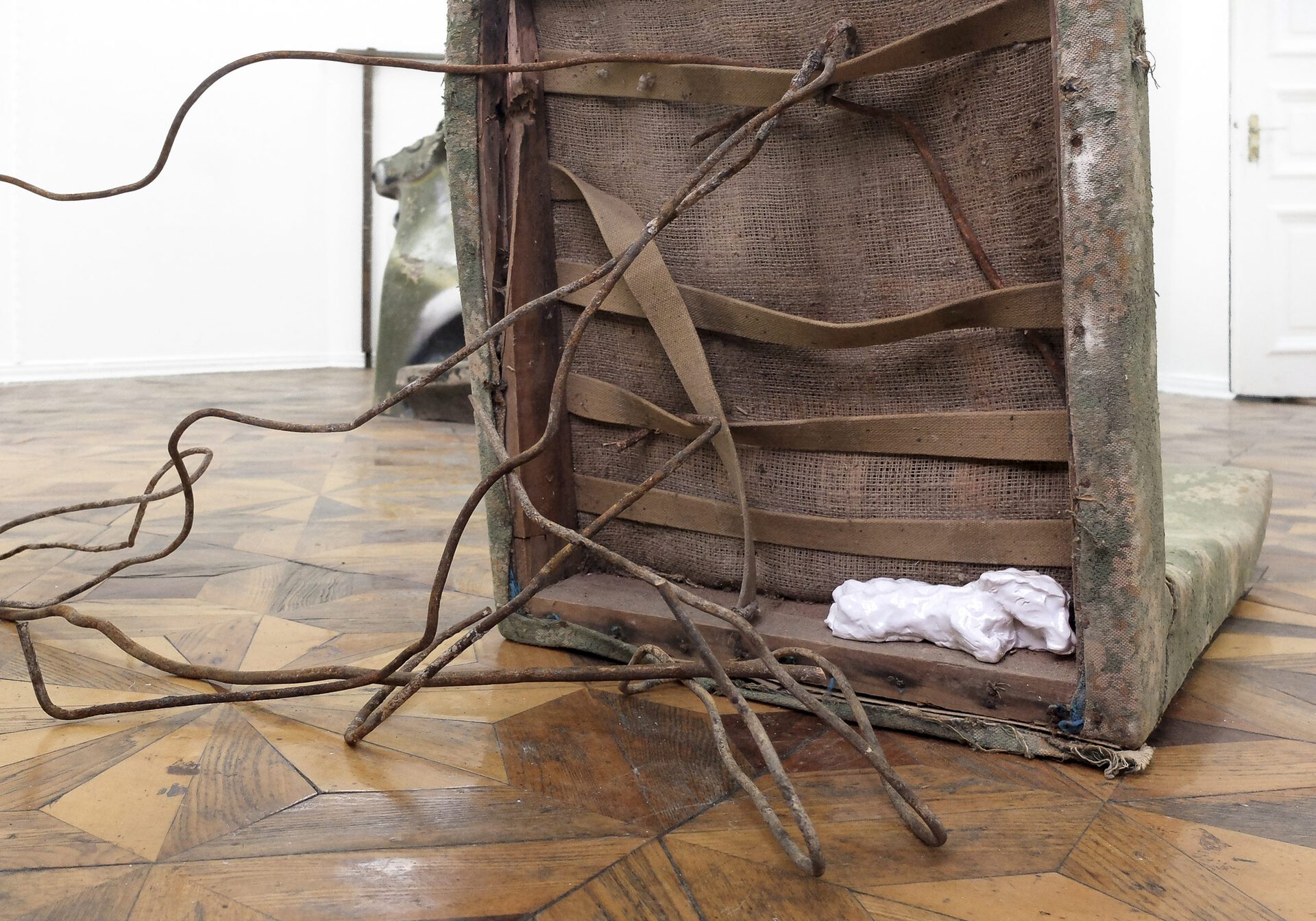 Sophie Jung, back supporting character with main lead unleashed (back) (detail), 2021. found chair tipped 90 degrees but still a chair, ceramic dogs, bent rebar poles resembling a hillside or a tangled dog leash.