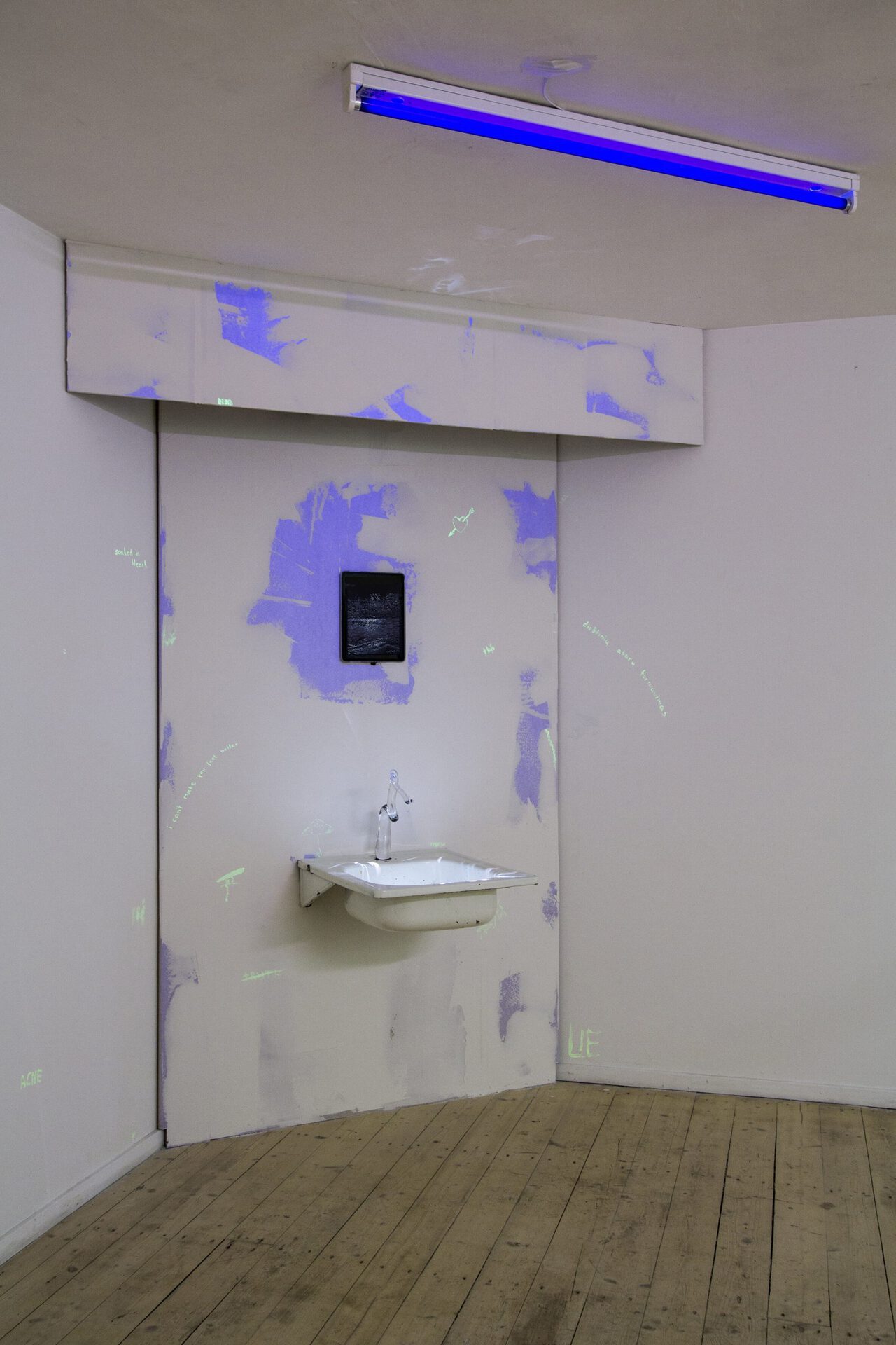 Liudmila (Miša Skalskis and Milda Januševičiūtė), Fountain. Video-installation, soundtrack, video-projection, drywall scraps, plaster, glass, discarded sink, iPad, UV lamp, 2021