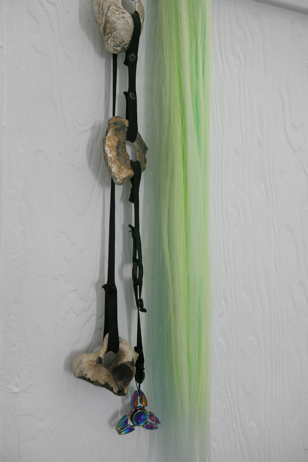 Rachel McRae, Ongoing reconfiguration of elements using a customizable system of elastic straps, athletic snaps and clips I, 2021, oyster shells mud-larked from the Thames with fidget spinners, hag-stones, and fluorescent hair-extensions, dimensions variable