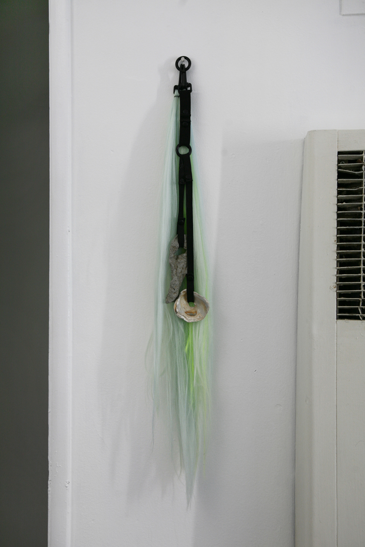 Rachel McRae, Ongoing reconfiguration of elements using a customizable system of elastic straps, athletic snaps and clips II, 2021, oyster shells mud-larked from the Thames with fidget spinners, hag-stones, and fluorescent hair-extensions, dimensions variable
