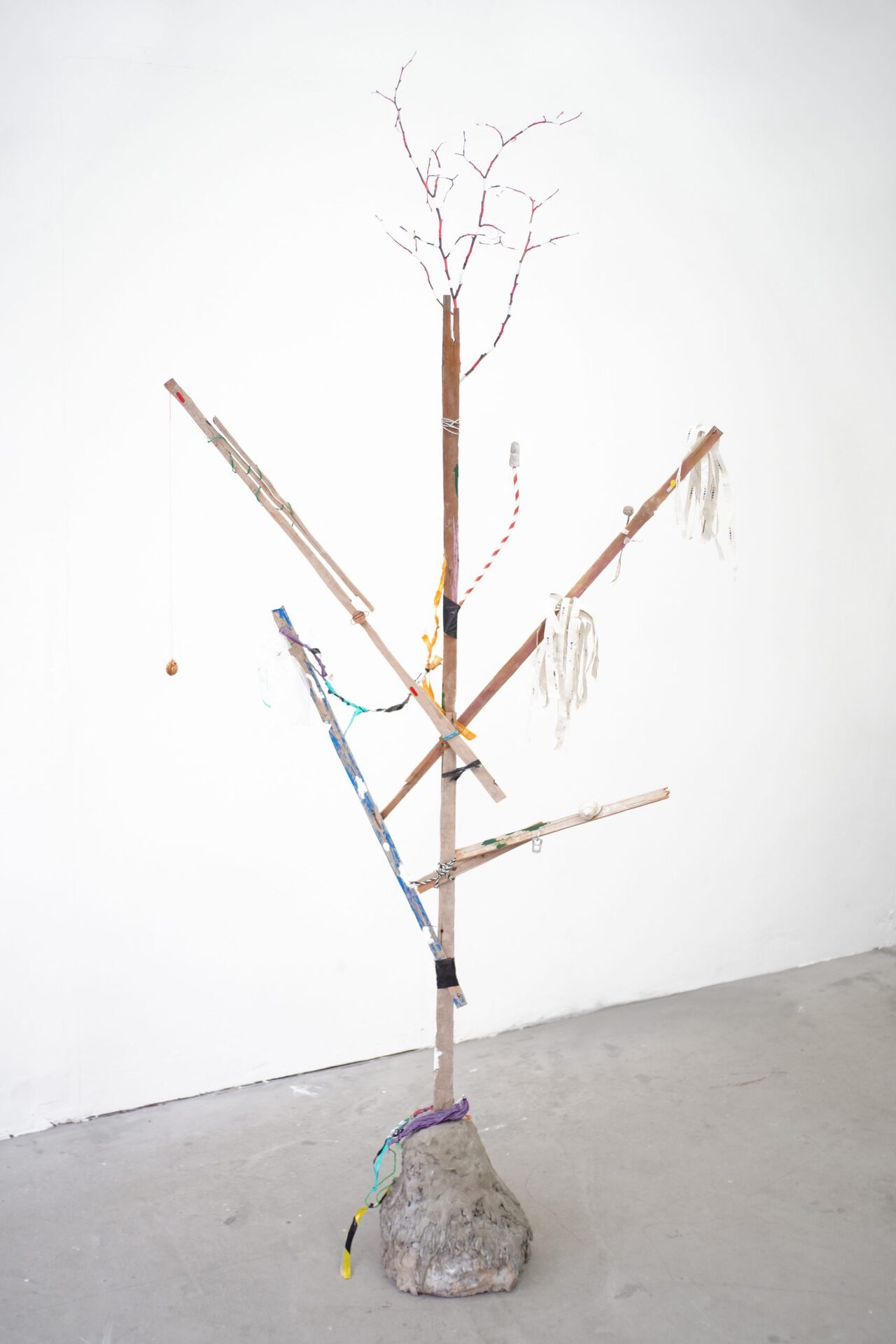 Ilona Balaga, Passerby, 2021, found wood, concrete, acrylic paint, plastic bags, 1p, tree branch, acorn, metal hanger, pull-tab, snail, string, rubber bands, gaffer tape, newspaper, straw, metal wire, sewing thread, peach kernel, paperclip, 195/70/27 cm