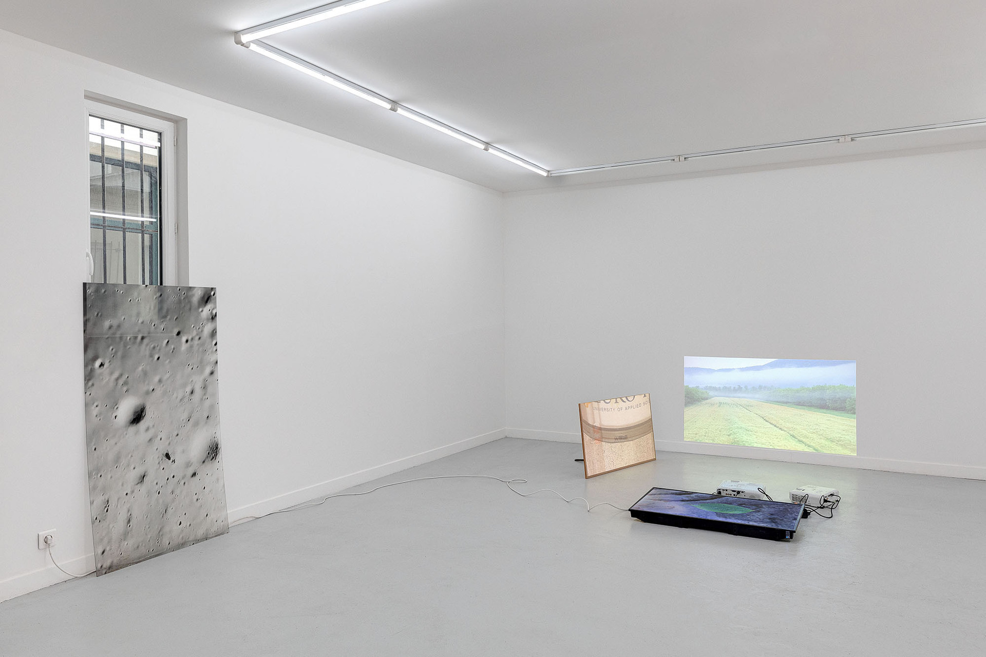 Left : Fly on Moon, 2019, UV print on plexiglas, 150 x 80 cm Right: Untitled, 2019-2022, installation with 2 projectors, 1 TV screen, electrical cables, selection of looping videos