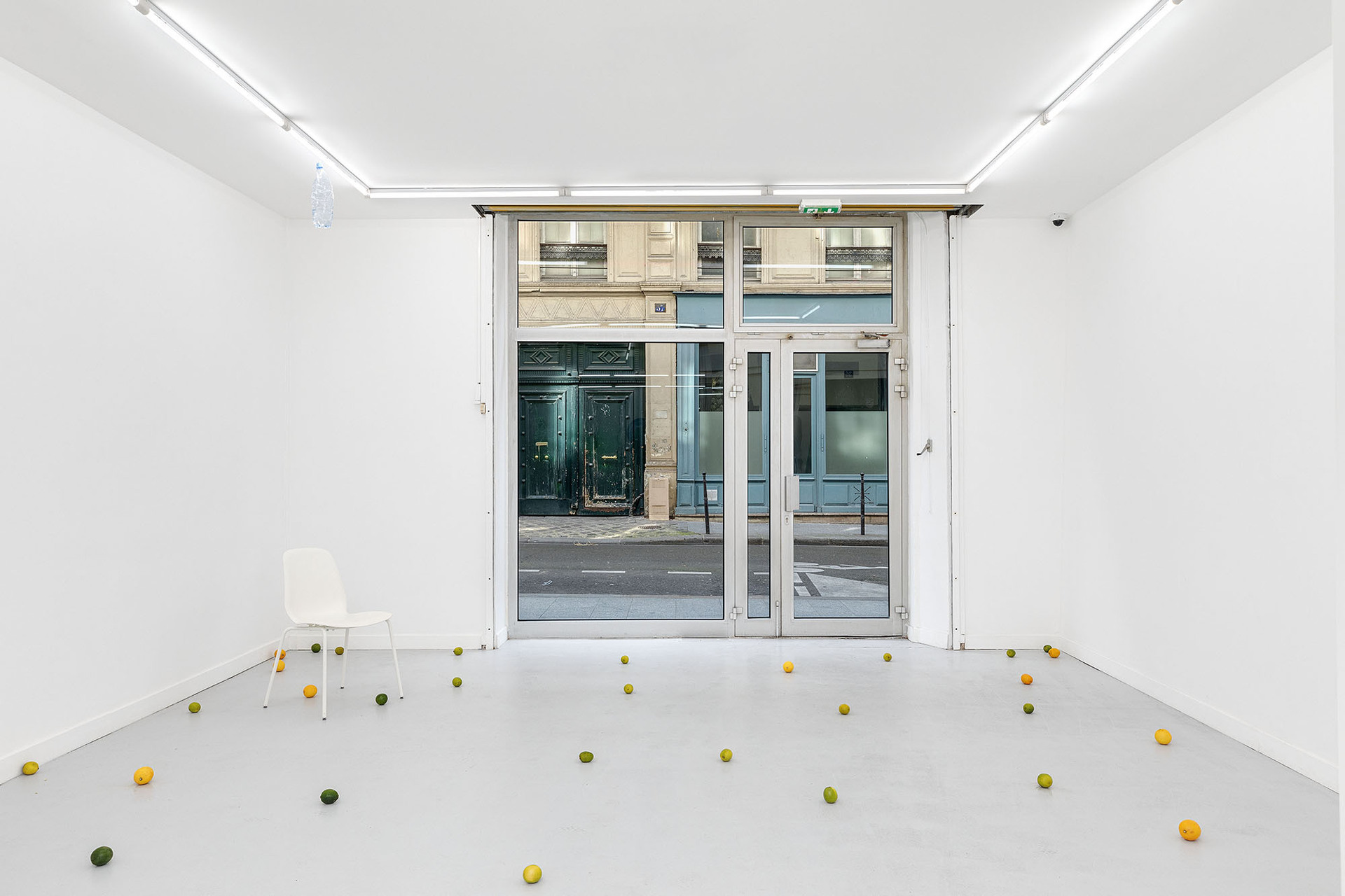 Left: Untitled (Rain), 2019 - 2022, plastic bottle, water, plastic chair, lemons, limes, variable dimensions Floor: Ritual with citrus fruit, 2019 - 2022, lemons, limes, variable dimensions