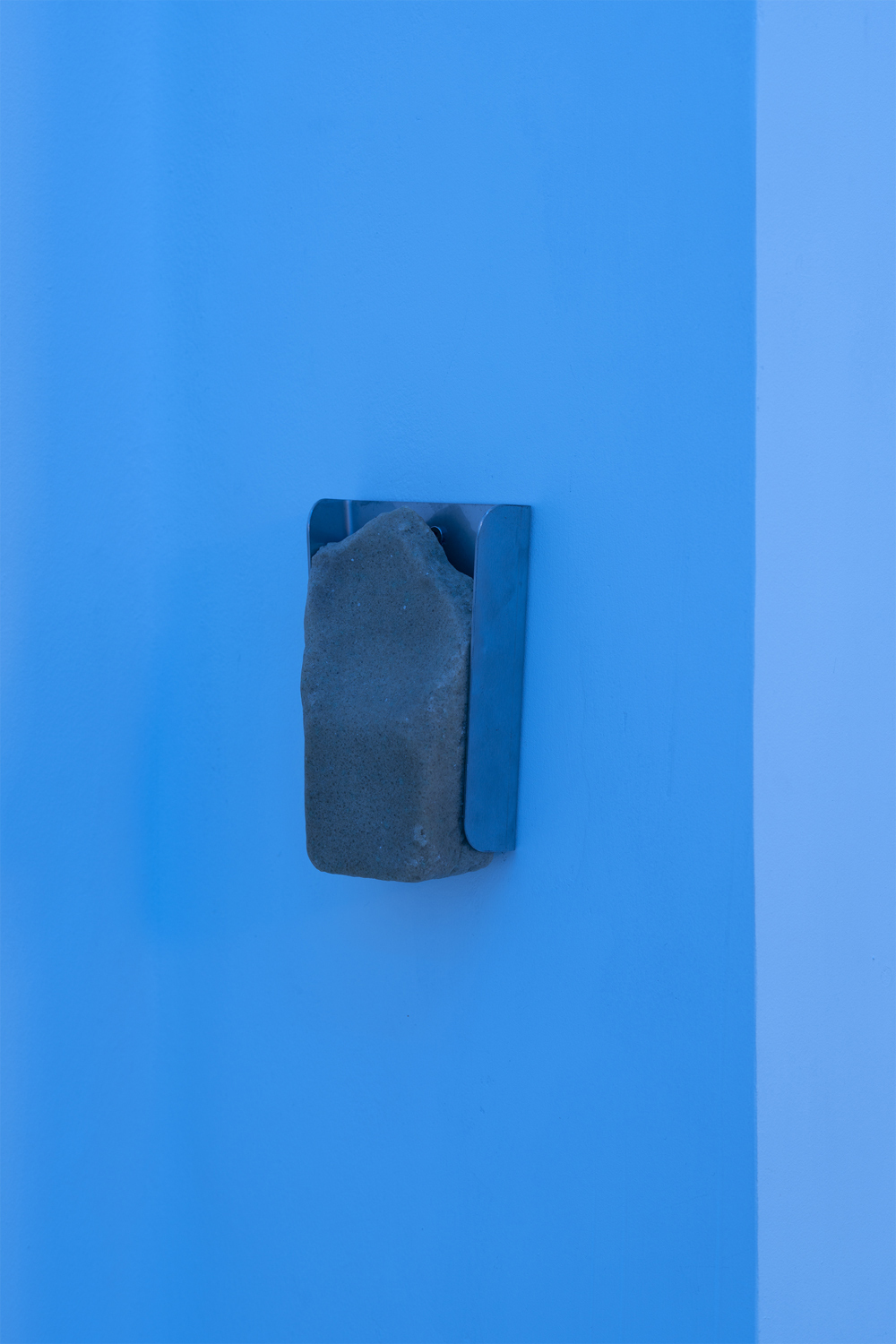 Fathia Mohidin &amp; Adele Kosman, Licking Stone, 2022 (Lick stone, stainless steel hanger, 17 x 11 x 5.5 cm).