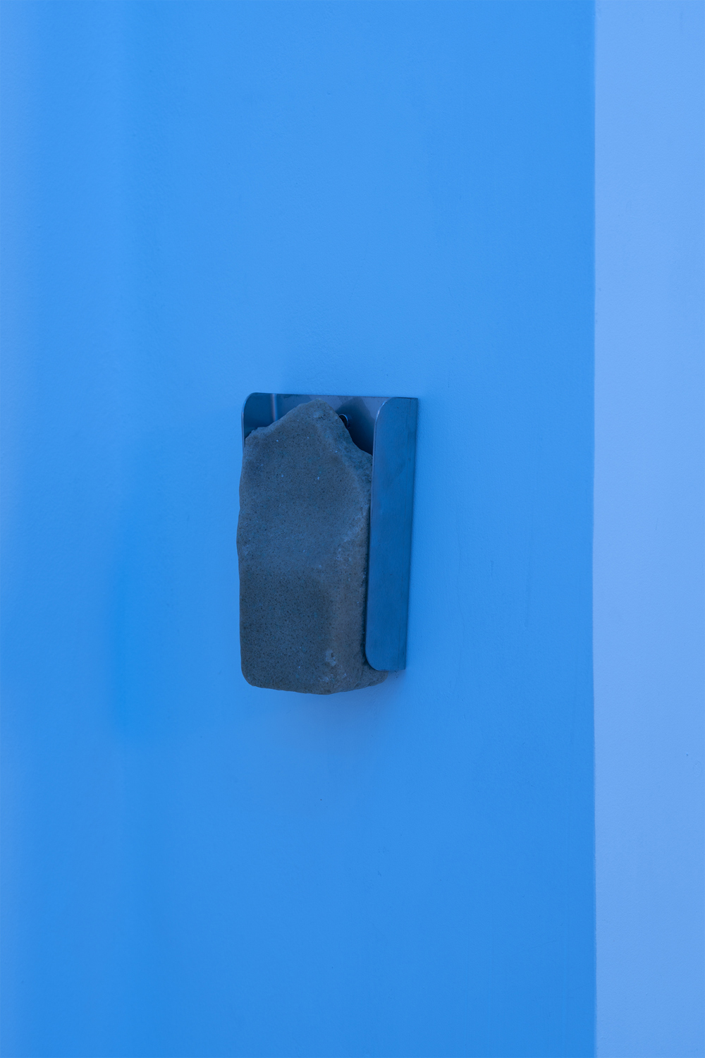 Fathia Mohidin & Adele Kosman, Licking Stone, 2022 (Lick stone, stainless steel hanger, 17 x 11 x 5.5 cm).