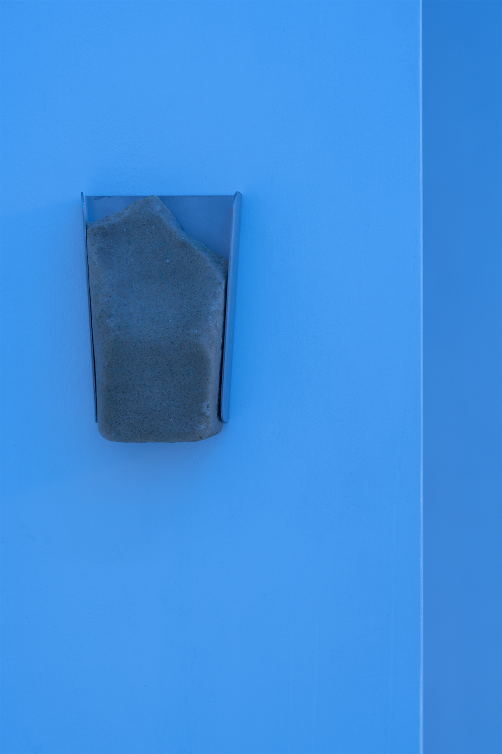 Fathia Mohidin & Adele Kosman, Licking Stone, 2022 (Lick stone, stainless steel hanger, 17 x 11 x 5.5 cm).