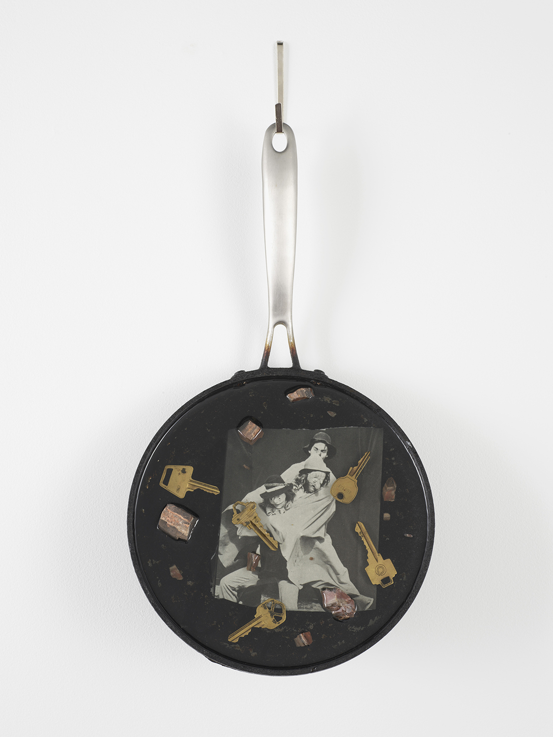 Zack Rafuls, Tondo (Mask Play) 2020 Frying pan, epoxy resin, found photograph, keys, & petrified wood 17.75 x 9.25 x 3 inches