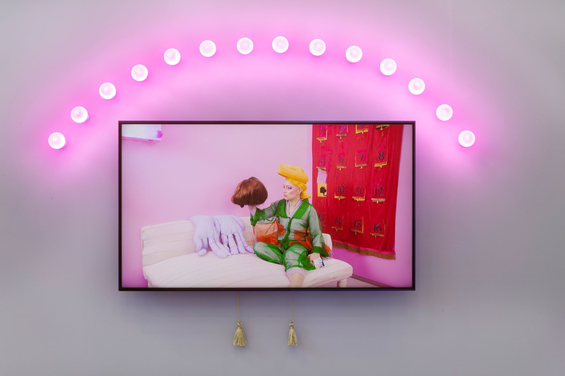 026 - Anouchka Oler Nussbaum - Exhibition view - Installation of The Drama More Show (Pilote), Video, pink light bulbs and golden tassels. The video is produced in the framework of "la vie bonne", a programme supported by the Centre national des arts plastiques and AWARE: Archives of Women Artists, Research and Exhibitions. Cnap collection. 2021