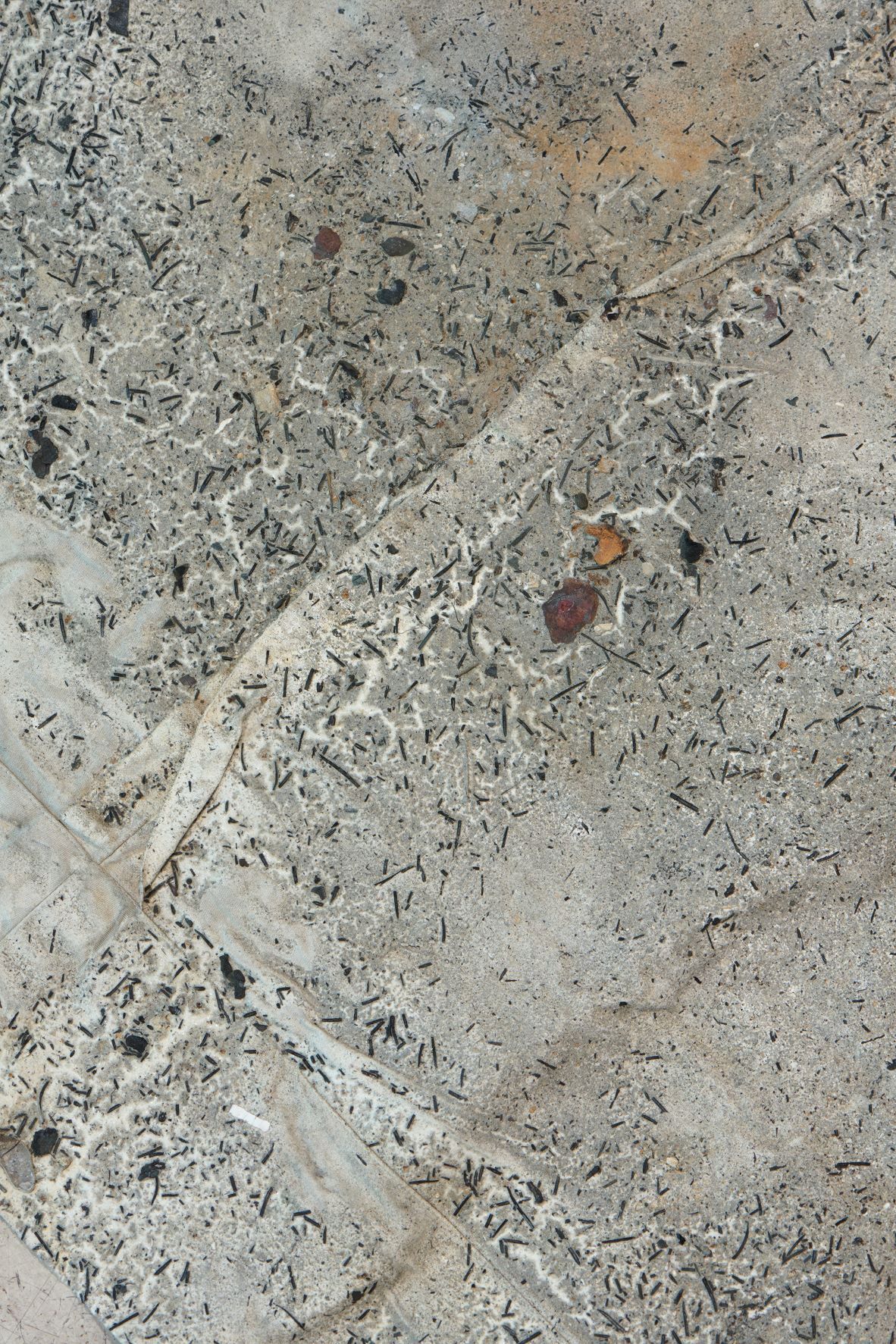 Dala Nasser: Red in Tooth, 2020 – 2021 – 2022 (detail). Discarded fabric, buried underground for 2 weeks to 3 months, ash, charcoal, rainwater. Kölnischer Kunstverein, 2022. Courtesy: the artist and Deborah Schamoni. Photo: Mareike Tocha.