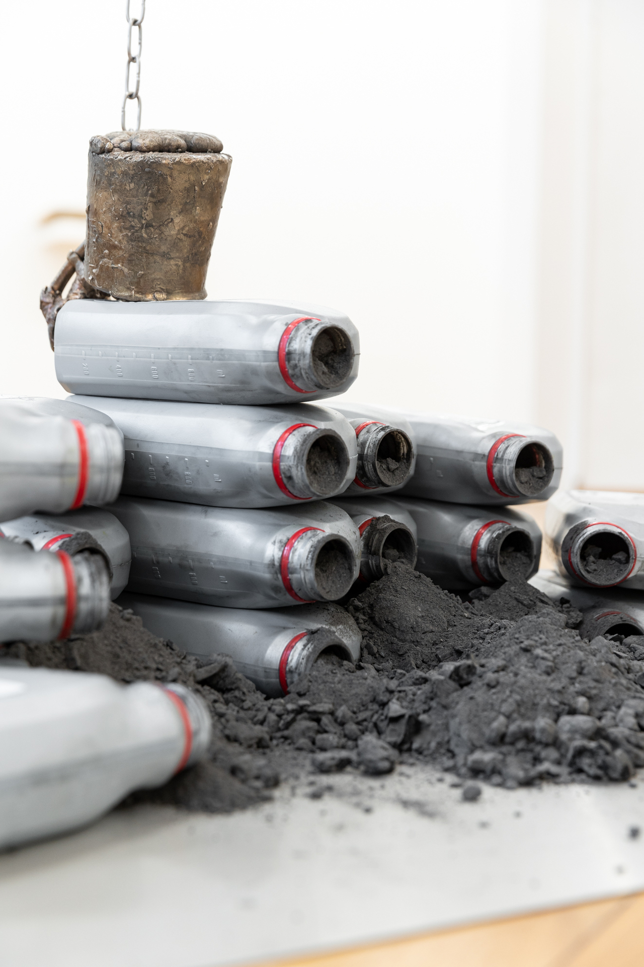 Laura Ní Fhlaibhín, "A tally of carbon mounts" (detail), 2022, bronze cast fungus, twin engine oil bottles, stainless steel chain, stainless steel carabiners, stainless steel sheet, carbon, wood ash, digitally embroidered poem by the artist on pile of incontinence bed-pads