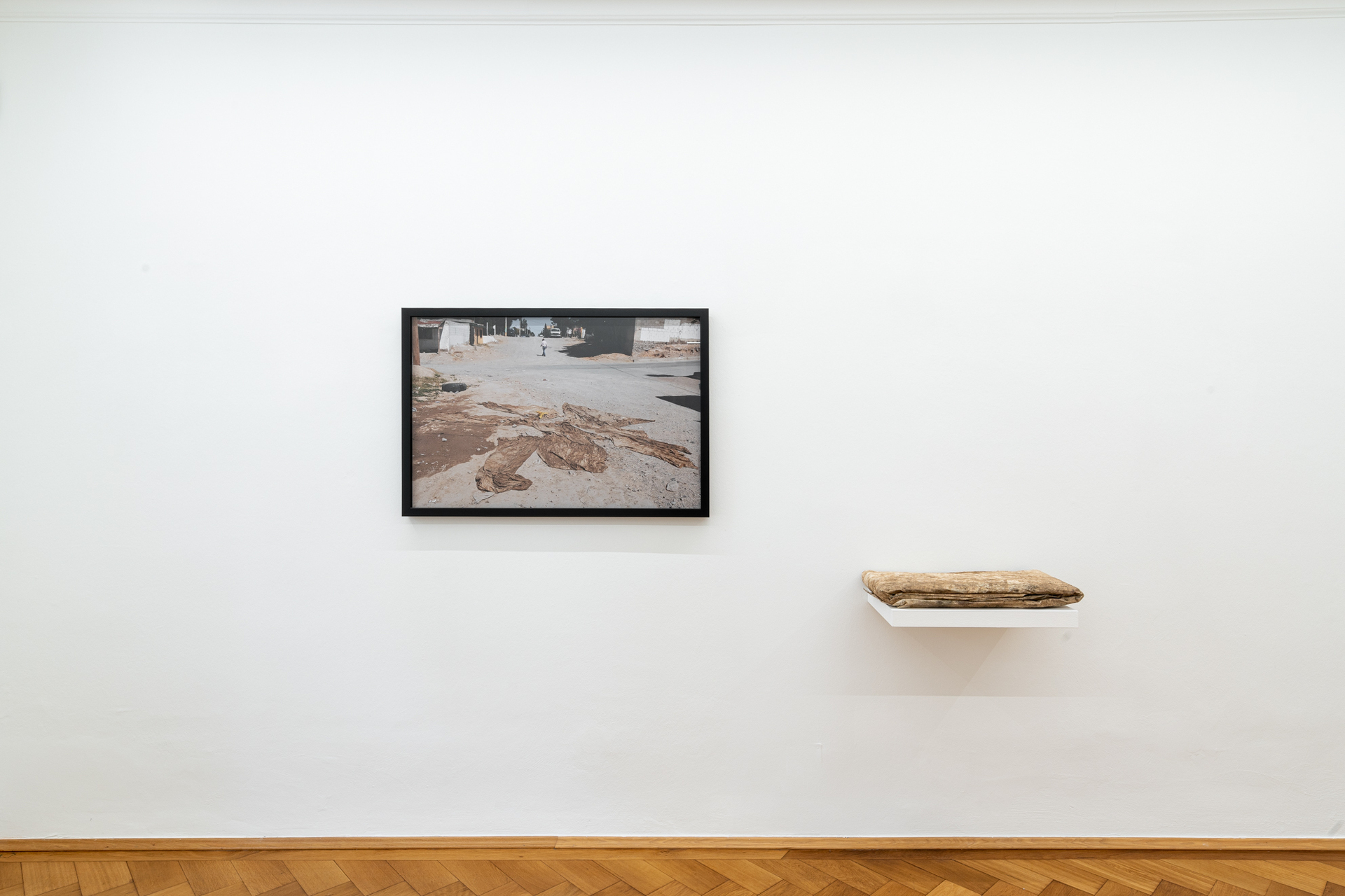 Teresa Margolles "Tela en el desierto (Fabric in the desert)", 2018, installation consisting of one color print and one folded fabric with residues from femicide sites gathered in 2009 in Ciudad Juárez, México, photo: 71,4 x 105 cm, framed, fabric folded: 4 x 60 x 37 cm, board: 5 x 55 x 36 cm