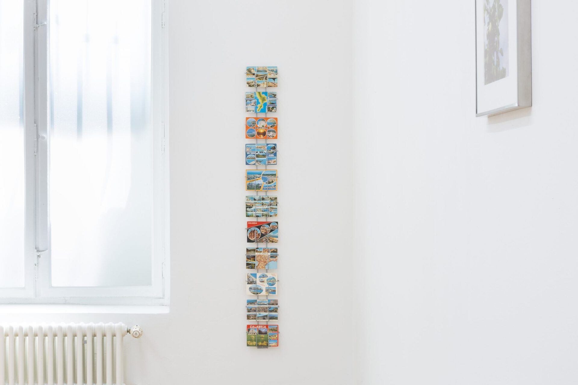 We are right down in the south now, 2022, Postcard rack, 11 found postcards, 133,5 x 16 cm
