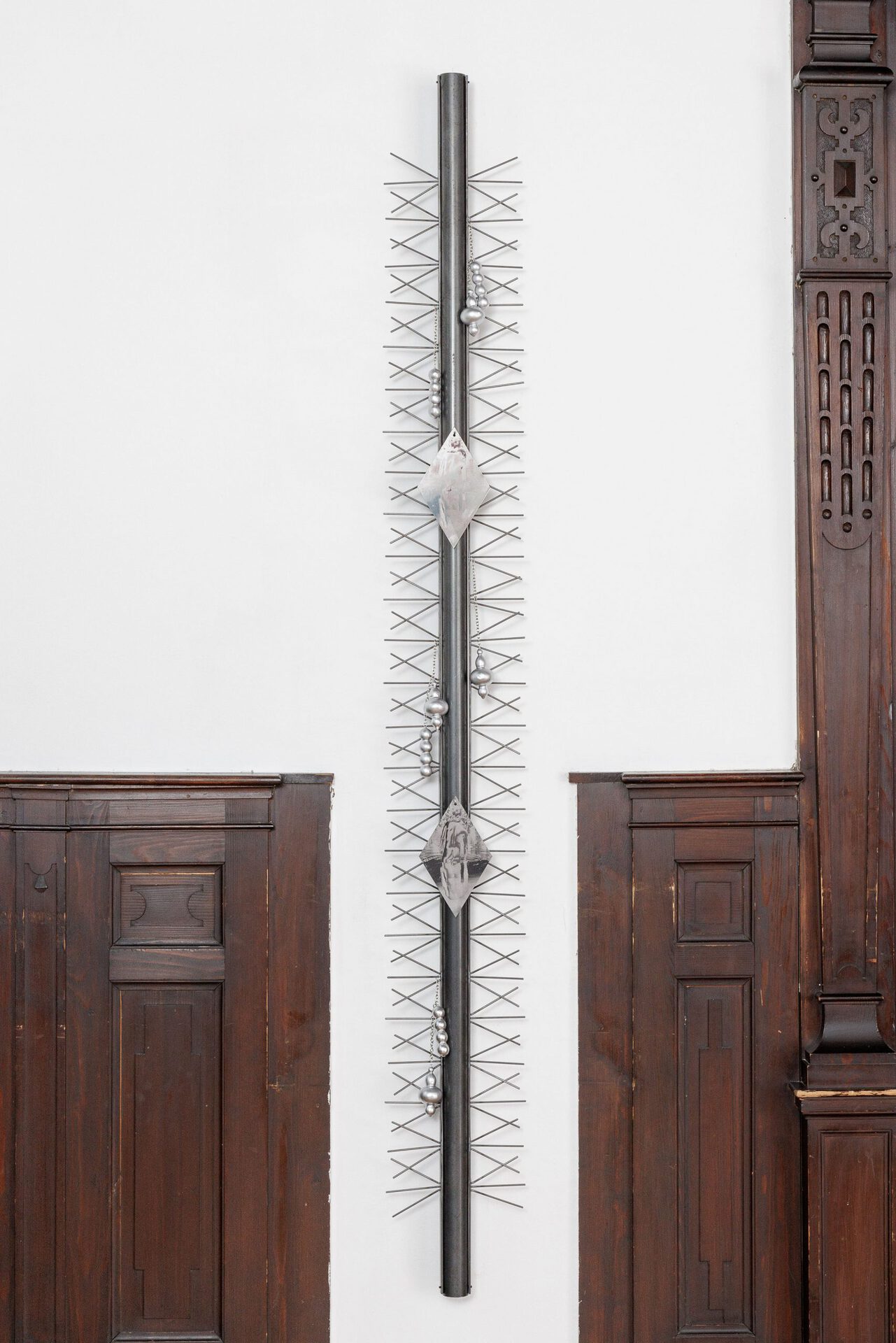 Sasha Auerbakh, Sebastian D. 2, 2022. Steel, UV-print on stainless steel, 3-D prints, plaster, paint, galvanized chains, 200cm x 9cm x 4cm.
