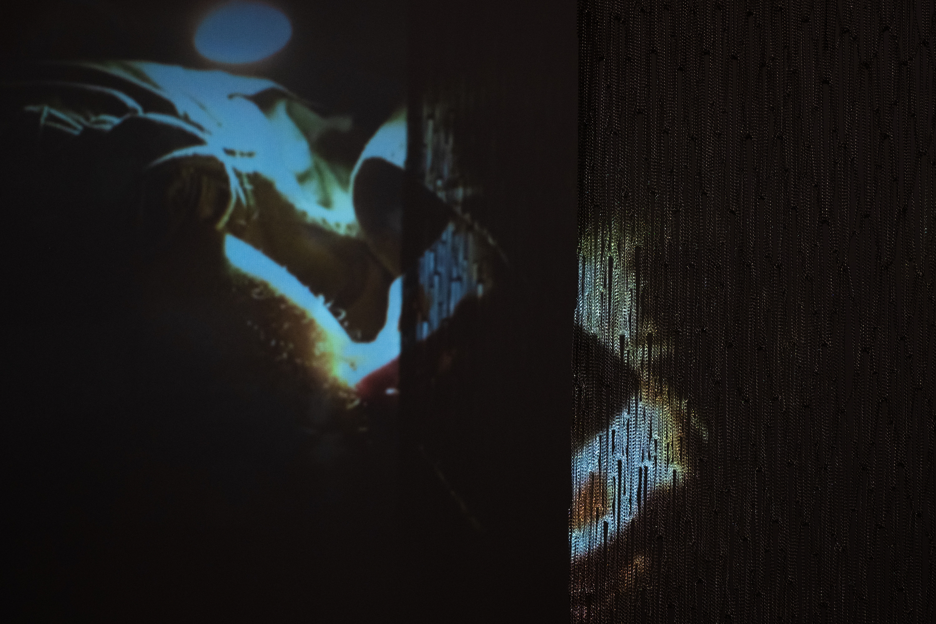 Elisa Florimond, projection “lights”, 2022 - ongoing series. video, 27 min and Maria Szakatz, “Untitled I”, 2022. Metal chains, 240 x 100 cm. Courtesy Rinomina and the Artists. Photo: Marcus Heim