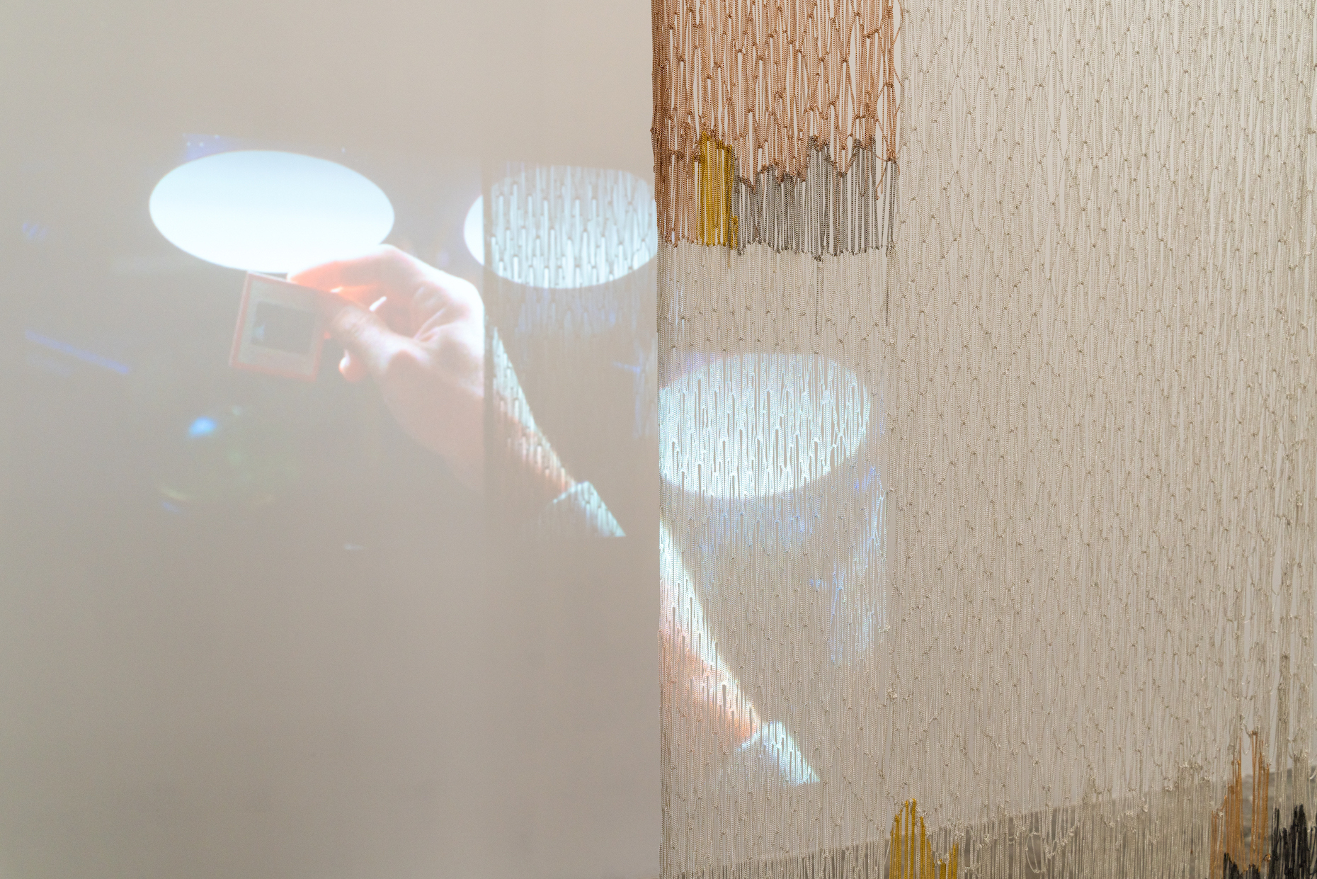 Elisa Florimond, projection “lights”, 2022 - ongoing series. video, 27 min and Maria Szakatz, “Untitled I”, 2022. Metal chains, 240 x 100 cm. Courtesy Rinomina and the Artists. Photo: Marcus Heim