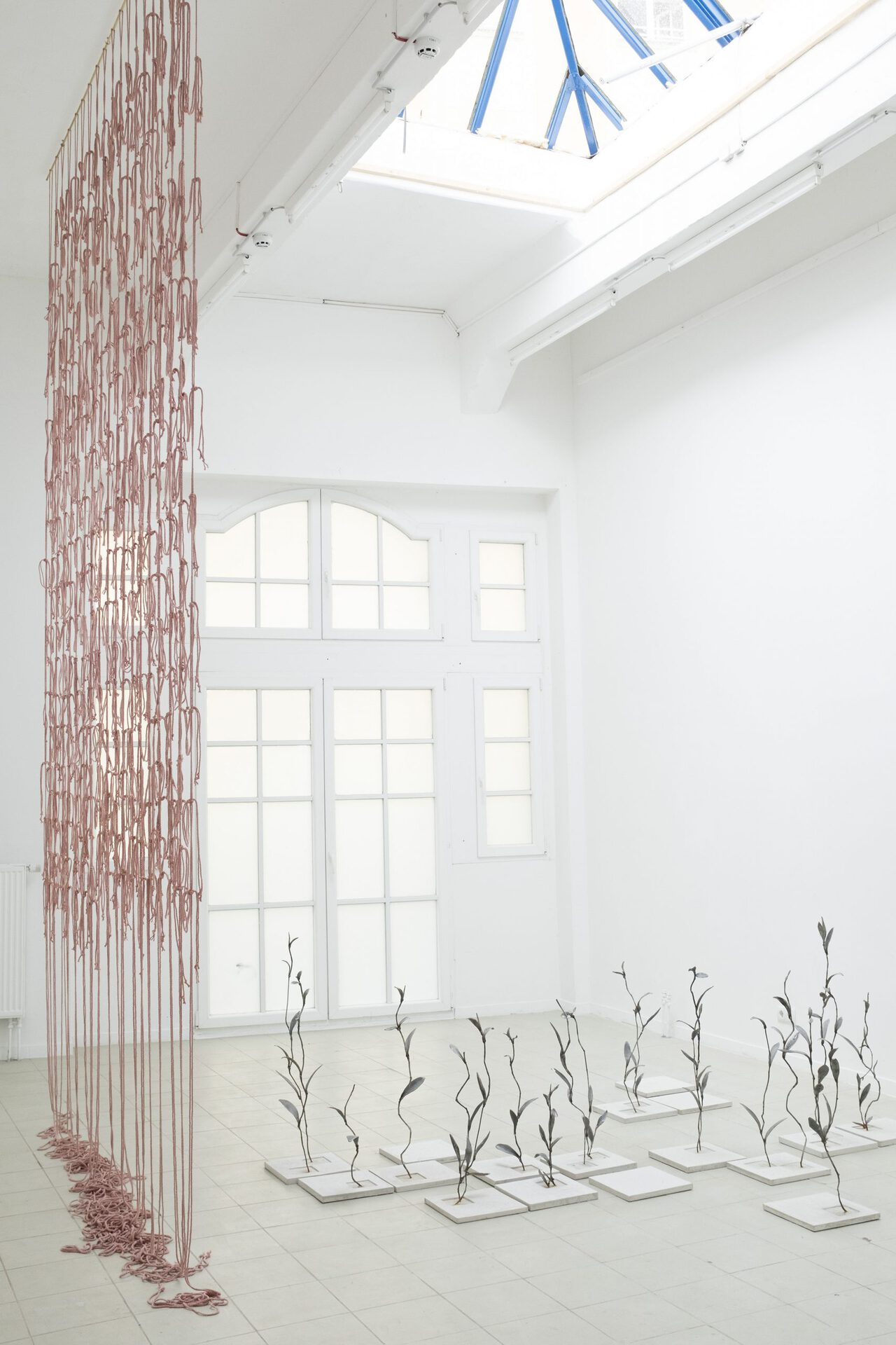 Exhibition View, Mirsini Artakianou, Untitled, 2022, Thread, Brass, Textile 6meter Long x200cm, Michal Fuchs, Von dem Land hinab zu gehen, 2021, iron cast, concrete, rust / tiles: each 30x30x2,5cm / plants: each 50-100cm high