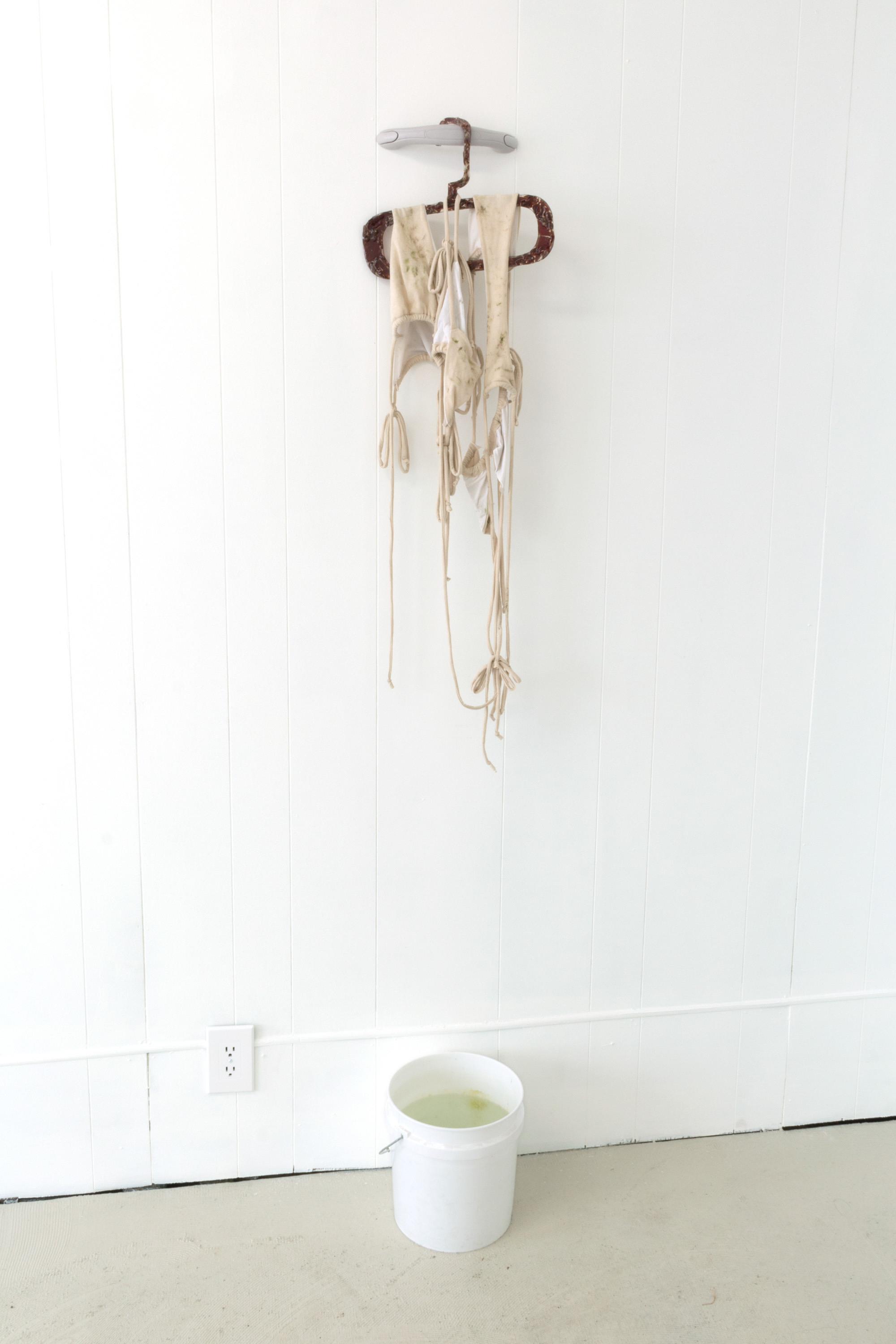 Maeve Coughlin, Untitled (airdry), 2022, Vinyl car grab handle, Jack Links jerky, resin, cotton jersey, grass, dirt, and lake water, Dimensions variable