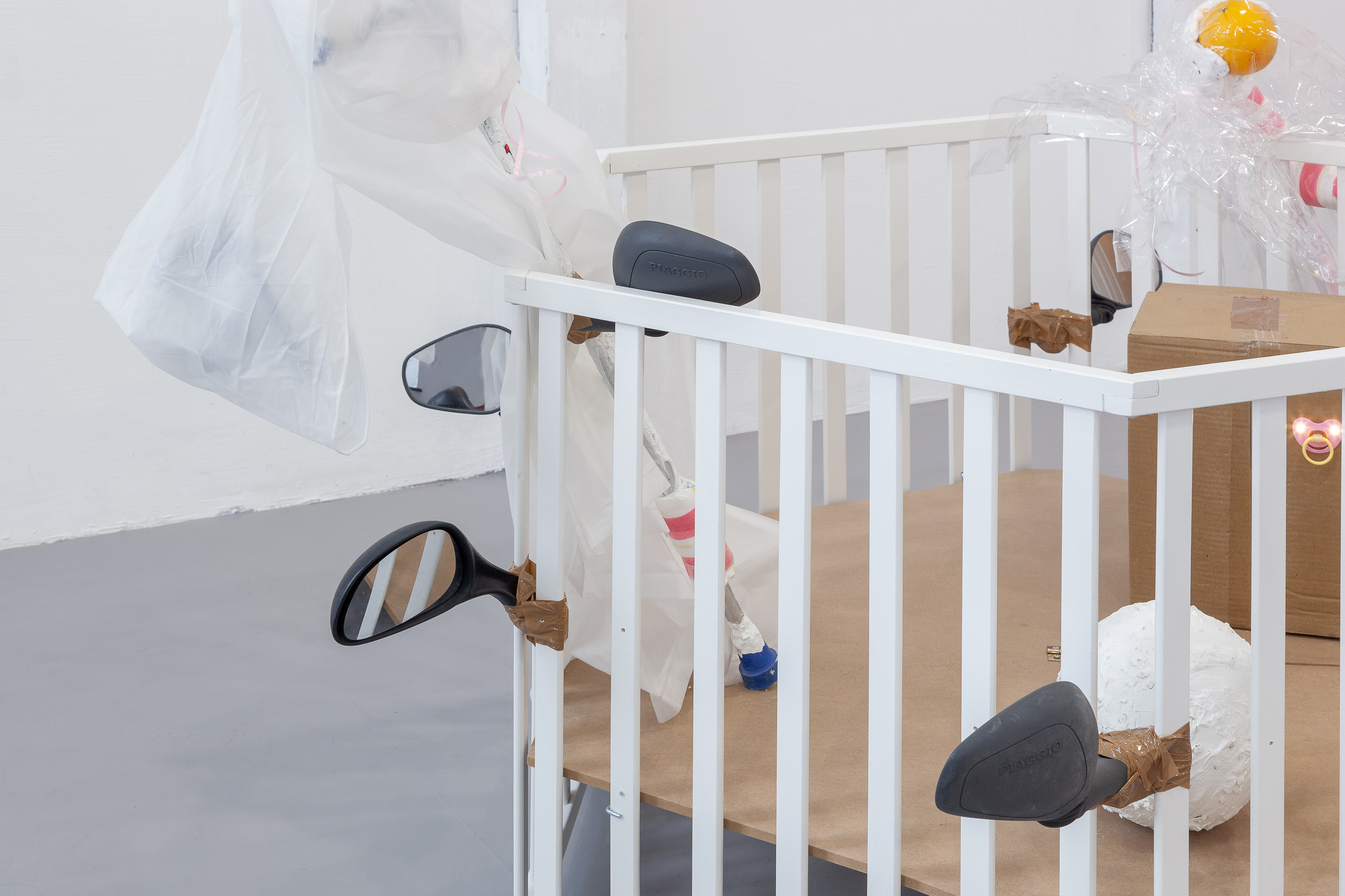 03. Paula Linke, Baby Shower City, playpen, scooter mirrors, tape, soft football, cement, oats, cardboard, led lights, wood, cellophane, orange, crutch, cement, diaper, rain cape, 2022 (Detail)