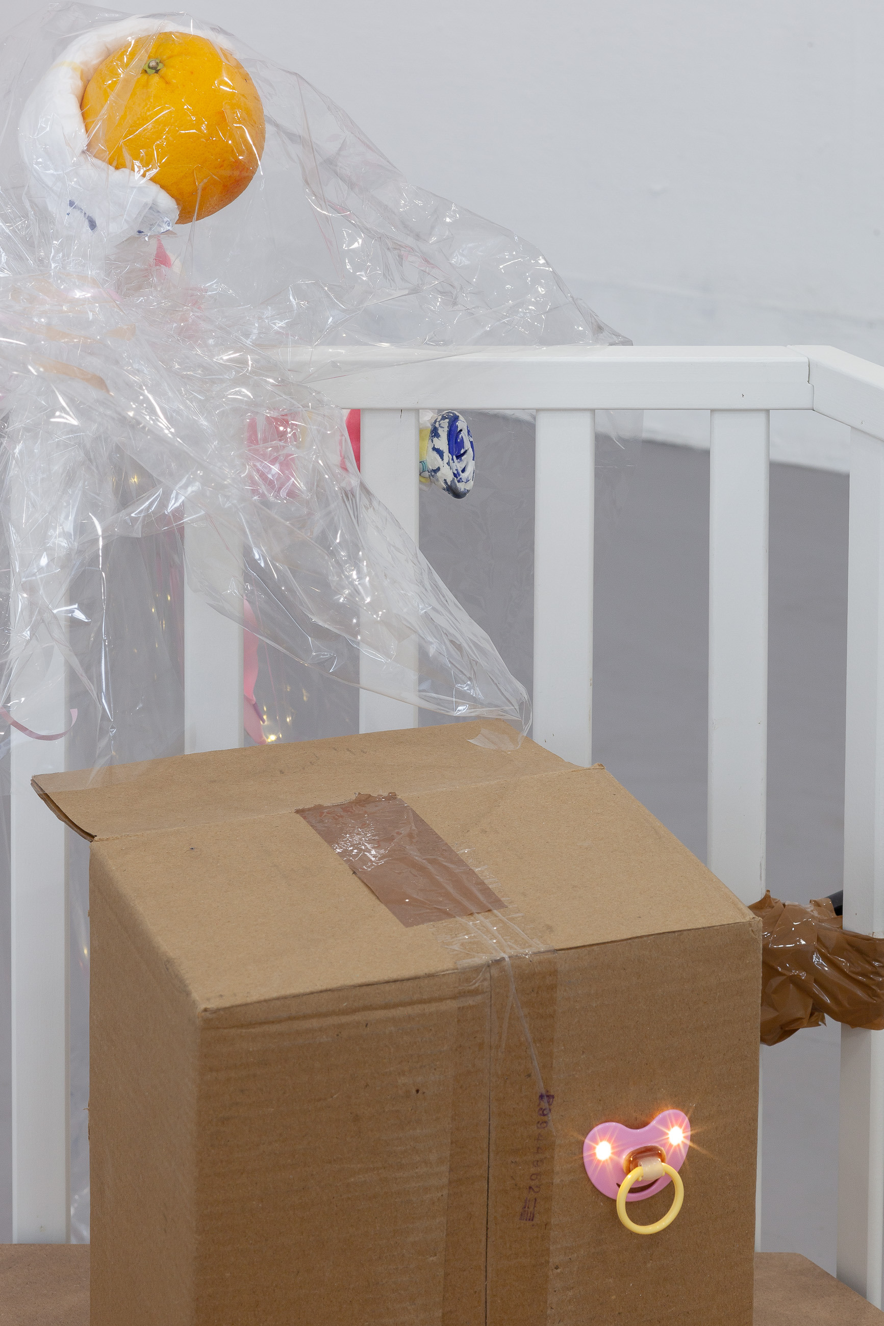 05. Paula Linke, Baby Shower City, playpen, scooter mirrors, tape, soft football, cement, oats, cardboard, led lights, wood, cellophane, orange, crutch, cement, diaper, rain cape, 2022 (Detail)
