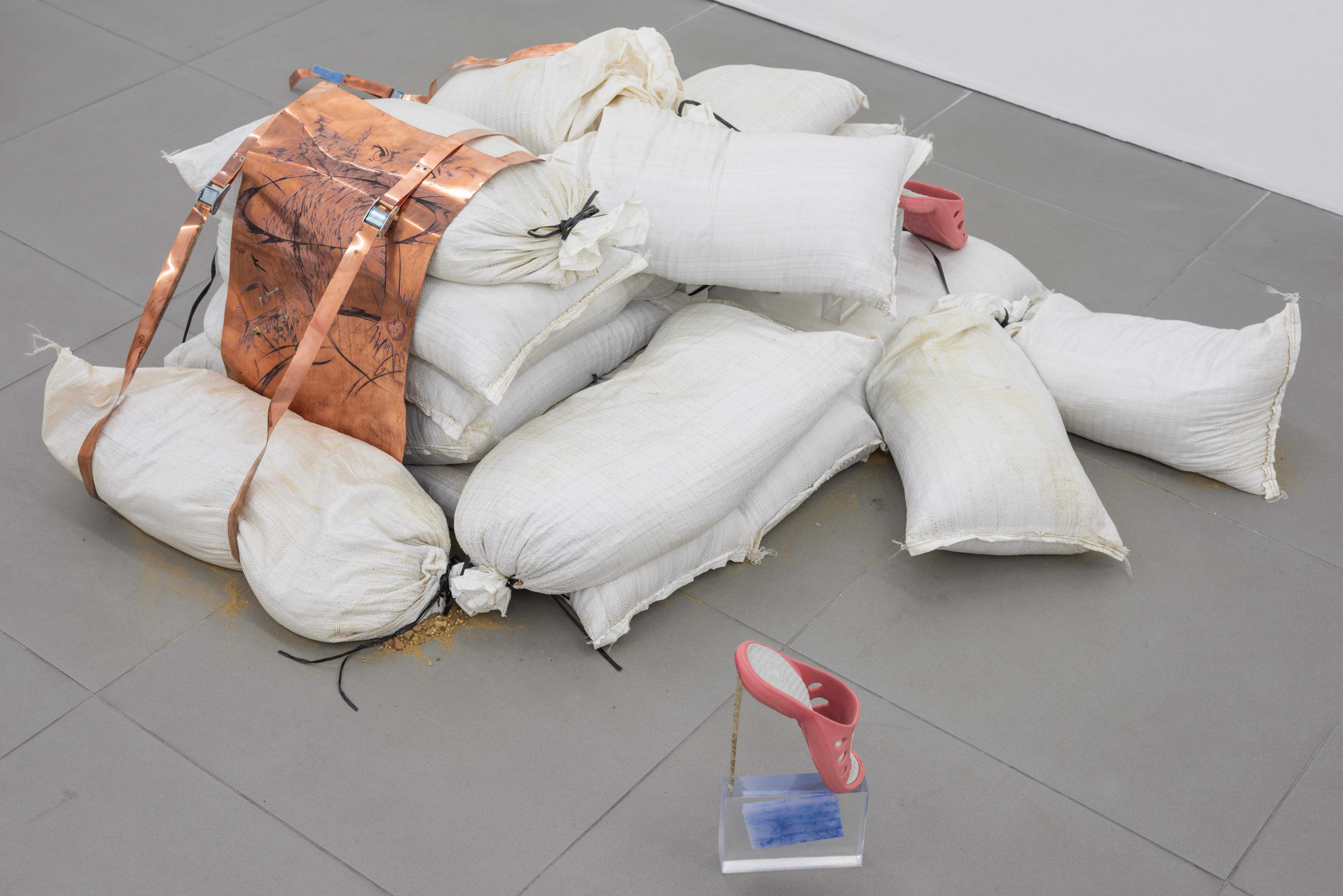 Agnė Jokšė & Anastasia Sosunova, Dance As You Wrestle, 2022, sand stacked in East London, sand bags, copper, ink, temporary tattoo stickers, epoxy resin, letters from x where she mentions Sodom and Gomorrah a lot, BELOVED slippers