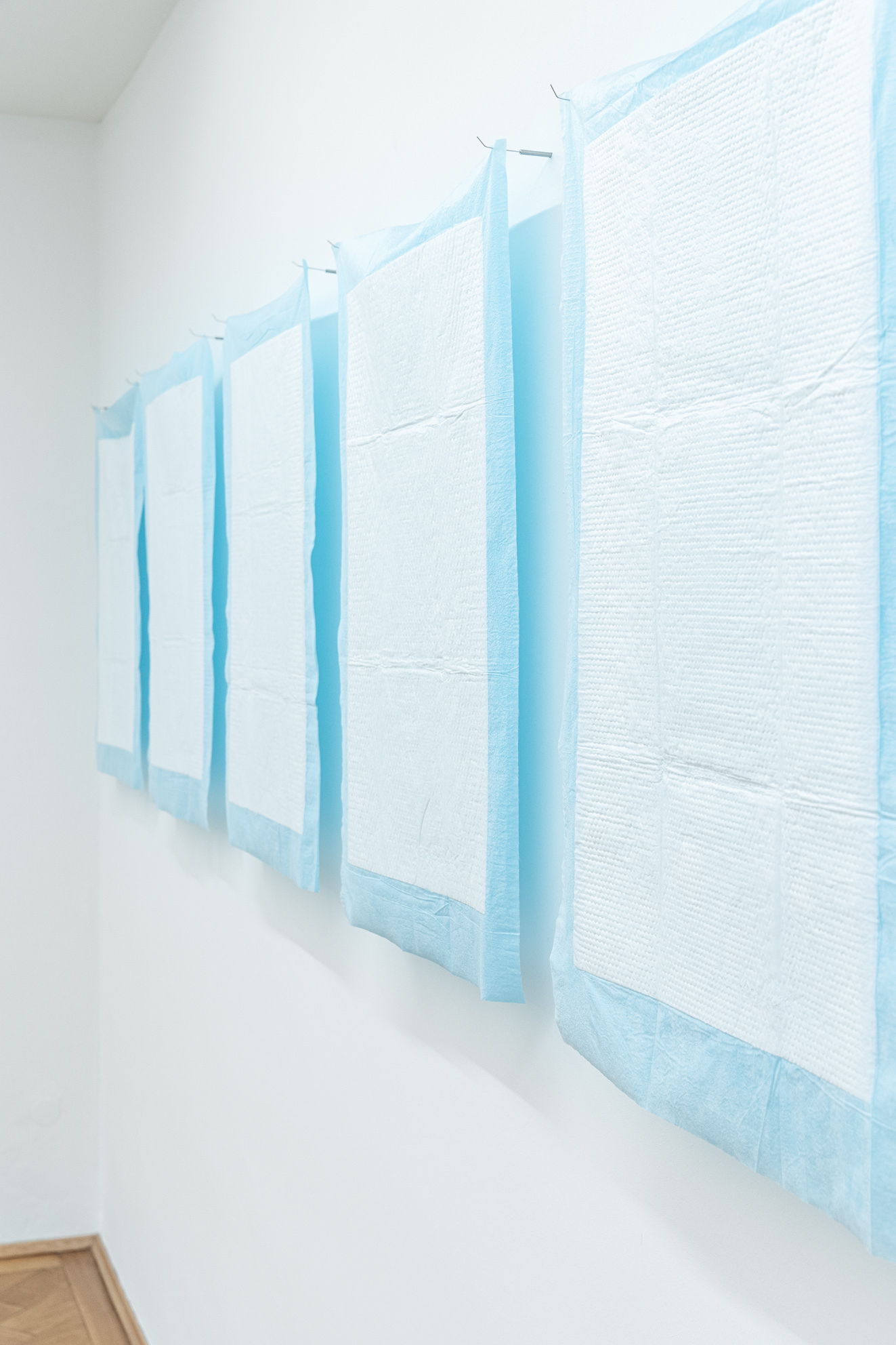 Laura Ní Fhlaibhín, "good luck" (detail), 2023, 7 digitally embroidered incontinence pads, held with stainless steel surgical seekers. Handwritten wish written by Rita Hurney, Laura’s grandmother, 60 x 90 cm