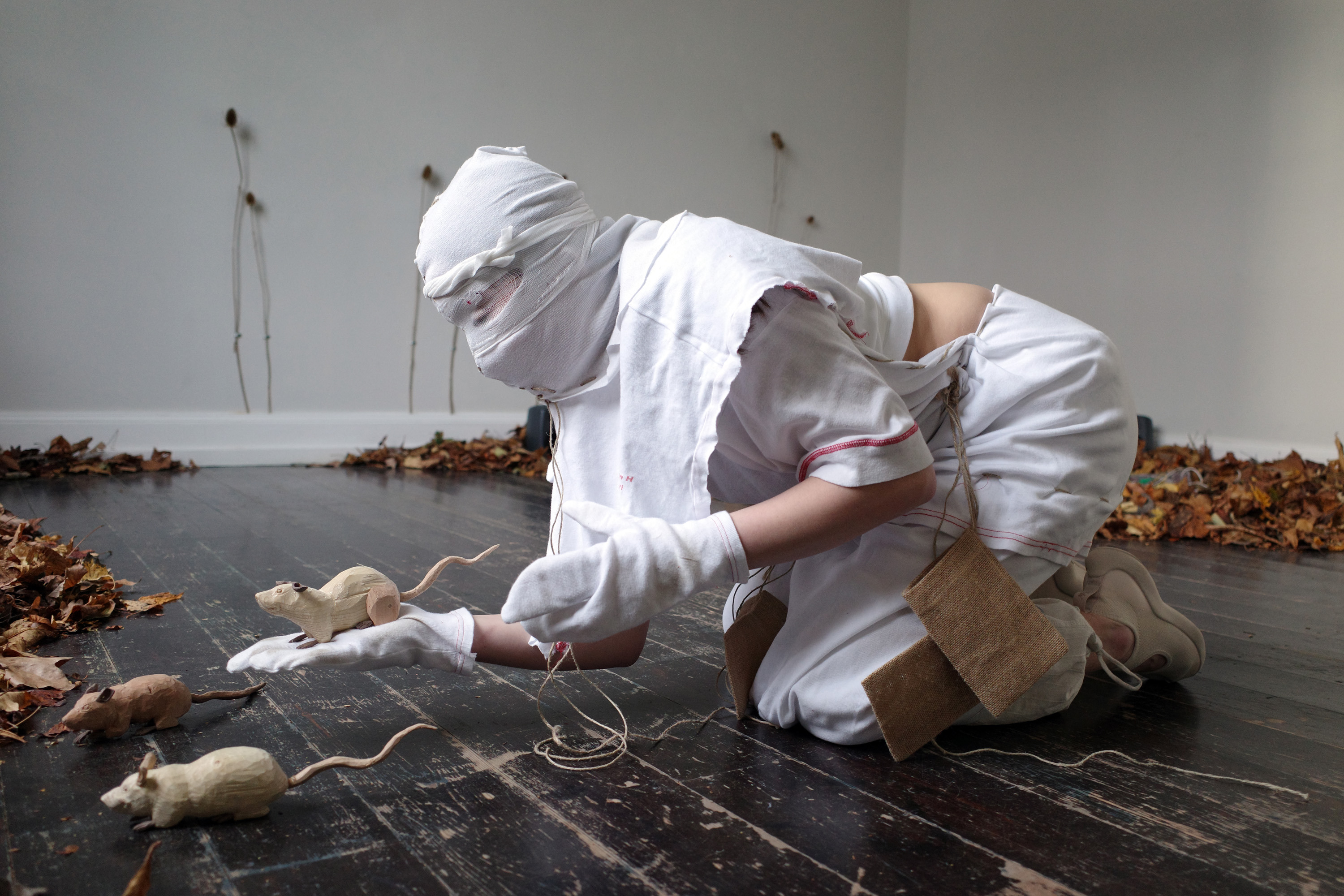 0, 2023, Anders Aarvik, Ayshan Qvortrup, Aske Hvitved. Performance (with Ayshan Qvortrup), installation of unfiltered leafs, teasels (dipsacus) attached with cable clamps, sewn patient clothes, jute, and wooden rodents (carved by Aske Hvitved)