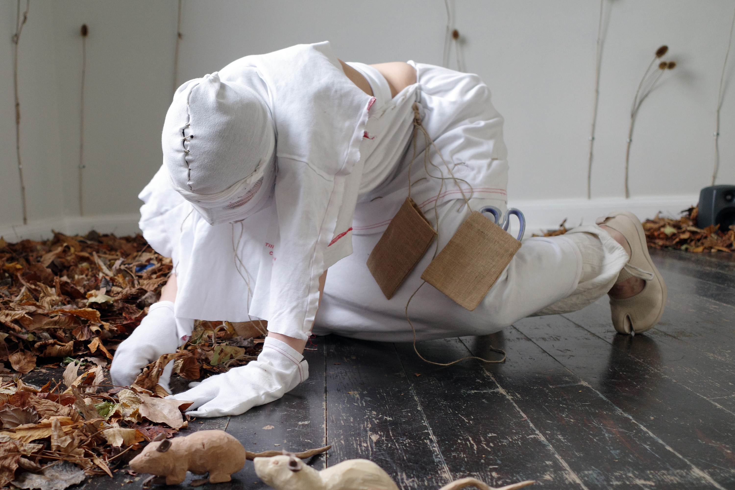 0, 2023, Anders Aarvik, Ayshan Qvortrup, Aske Hvitved. Performance (with Ayshan Qvortrup), installation of unfiltered leafs, teasels (dipsacus) attached with cable clamps, sewn patient clothes, jute, and wooden rodents (carved by Aske Hvitved)