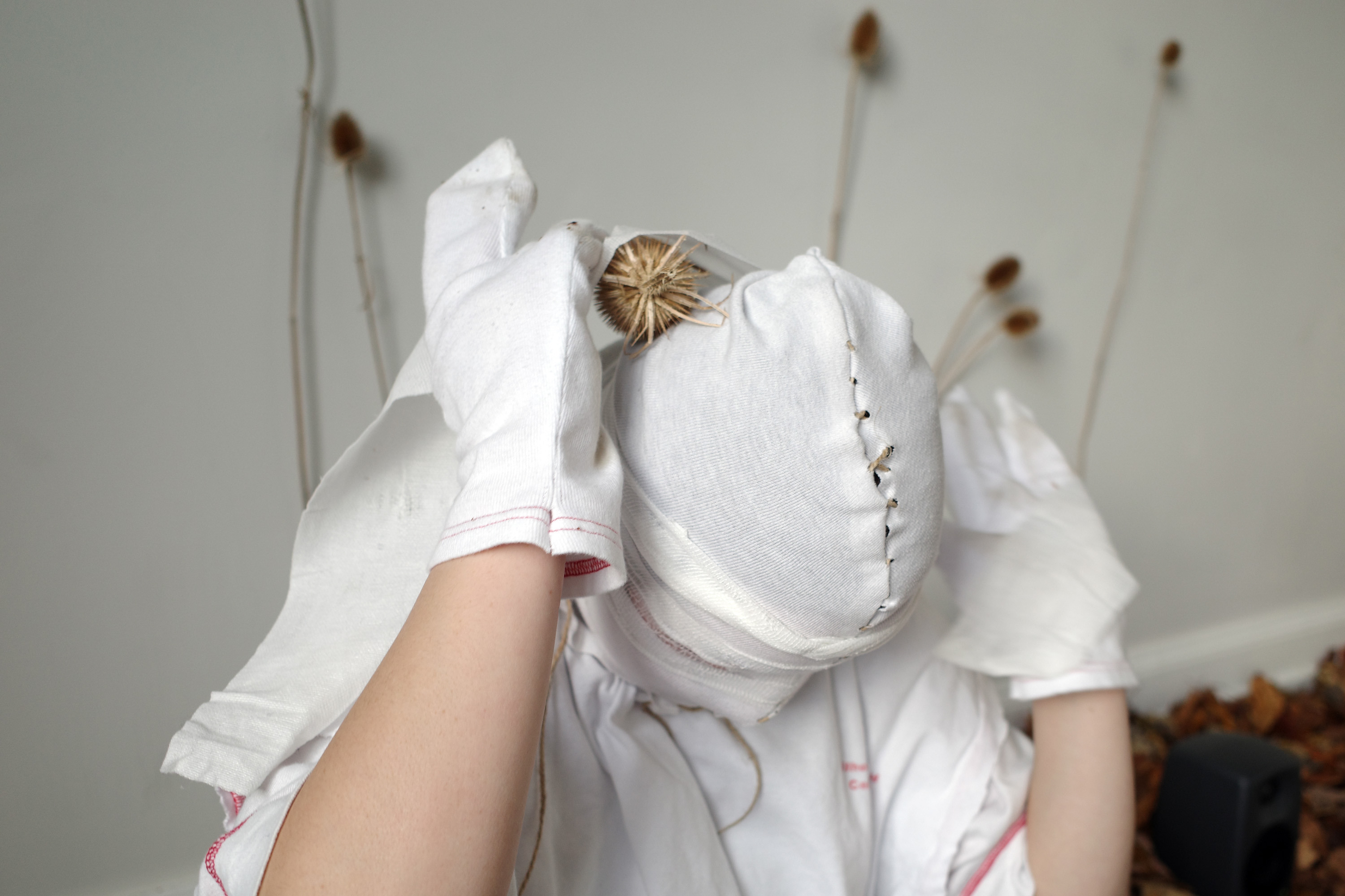0, 2023, Anders Aarvik, Ayshan Qvortrup, Aske Hvitved. Performance (with Ayshan Qvortrup), installation of unfiltered leafs, teasels (dipsacus) attached with cable clamps, sewn patient clothes, jute, and wooden rodents (carved by Aske Hvitved)