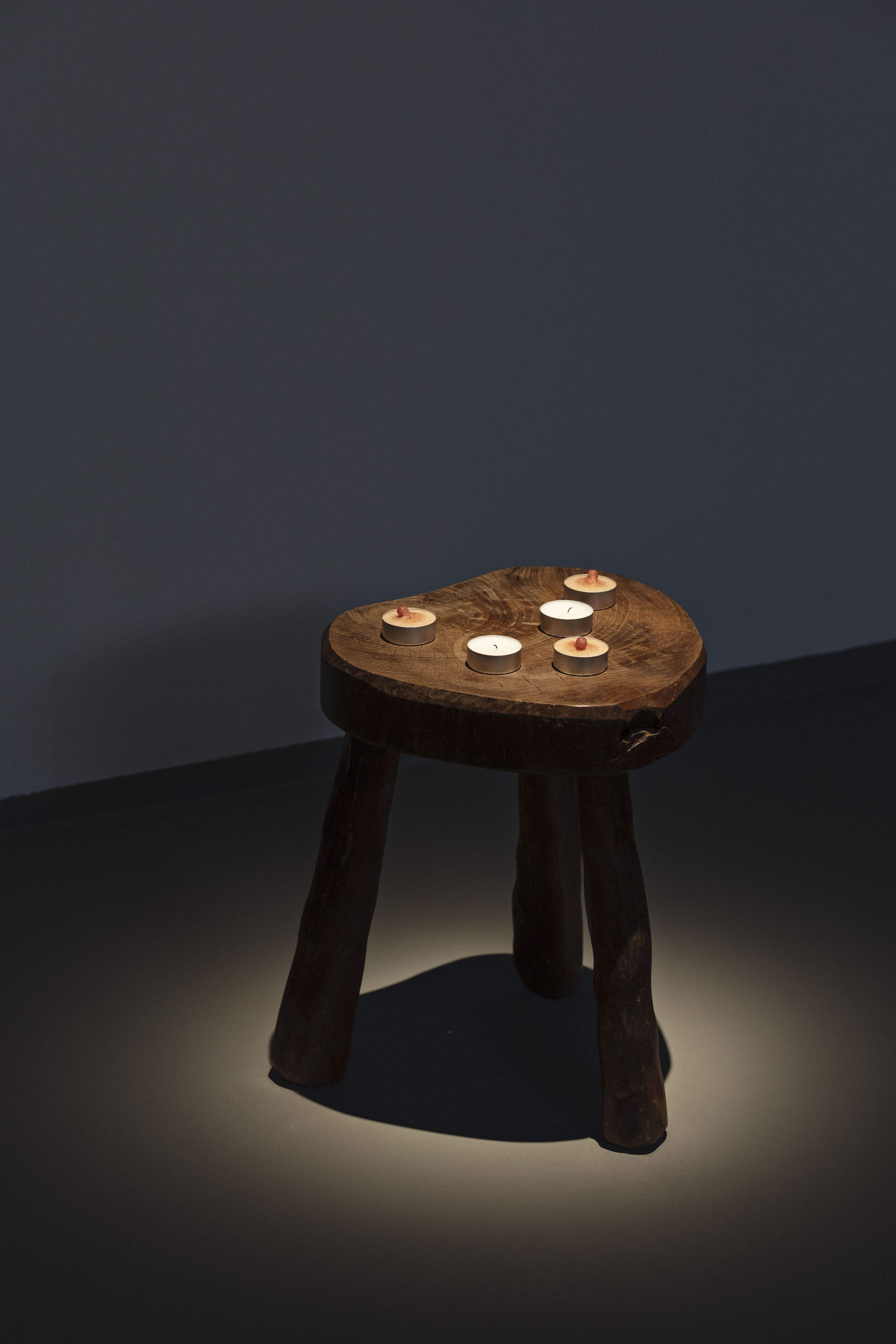 Young-jun Tak: One More Please, 2022. Installation view O—Overgaden, 2023. Wooden milking stool, votive candles, silicon, paint, aluminium, and glue 39 × 35 × 35 cm. Courtesy of the artist.  Photo: Laura Stamer