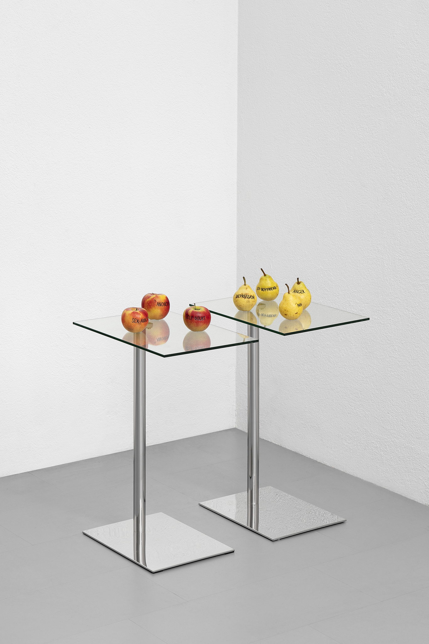 Paolo Bufalini, Self-doubt, Sex-addiction, Anorexia. Glass and steel table, tattooed Kanzi apples, 75x34x50cm; Anger, Ex-boyfriend, Depression, Paranoia, 2023. Glass and steel table, tattooed Kaiser pears, 75x34x50cm. Courtesy of the Artist and La Rada.