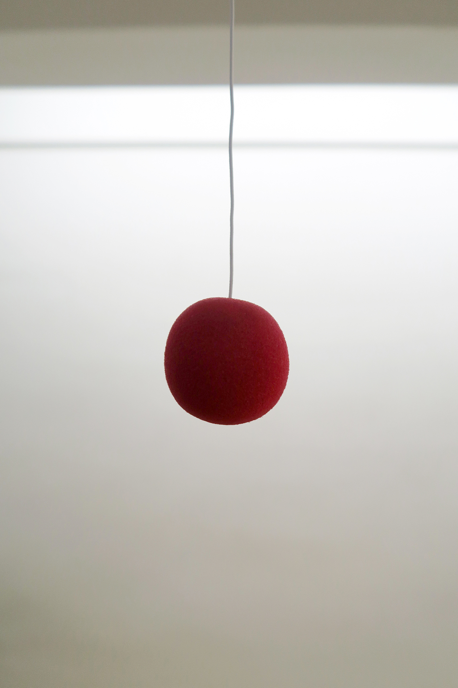 Clémentine Adou, Red dot, red nose, 2023, red nose, motor, elastic, 5 × 5 × 5 cm