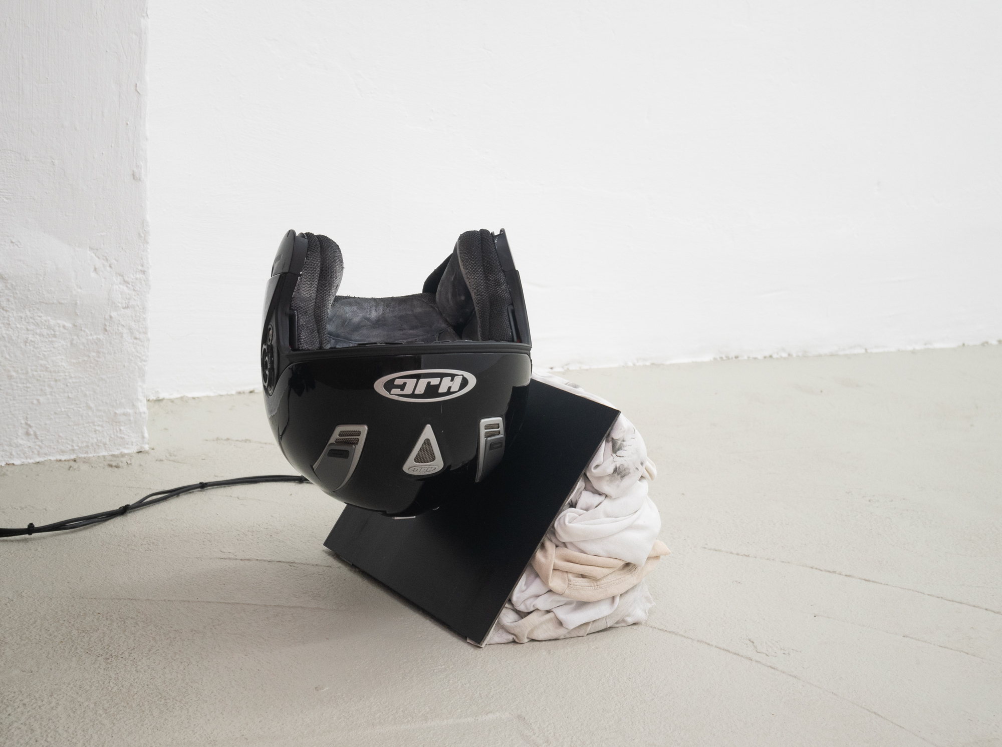 Clemens Tschurtschenthaler; fly on the wall (next doors drama); 2023; helmet, gesso, spray paint, waxed steel, textiles, media player, speaker, sound composition (09:44 min.); 39 x 31 x 41 cm