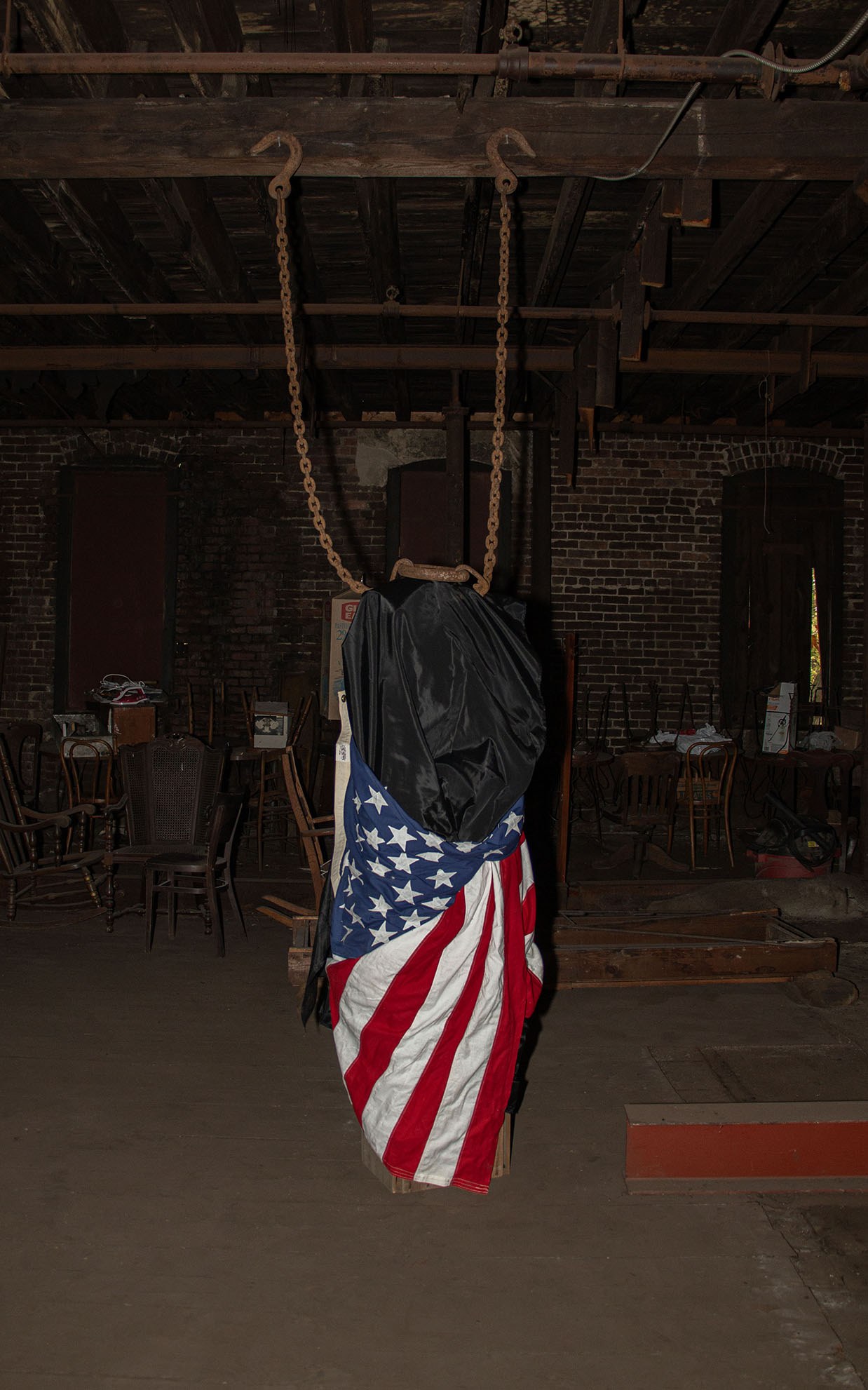 Tomm Roeschlein, untitled, 2023, flag, synthetic fabric, wood crates, rusty antique chain.