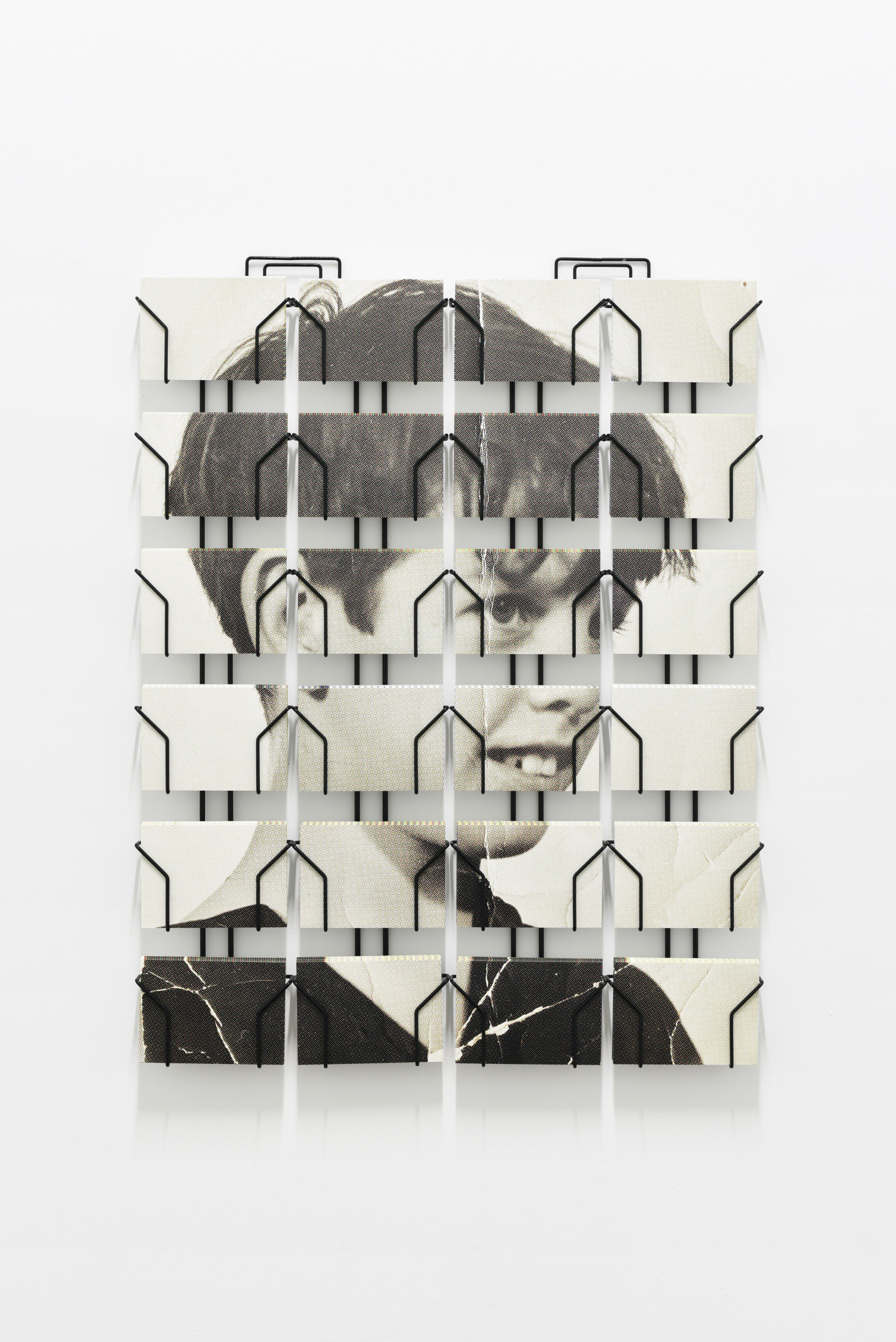 Ryan Gander, A Portrait of Aston Ernest as a boy, 2023, Two wall-mounted postcard racks displaying multiple postcards which create an image of the fictional character, Aston Ernest, as a child.
