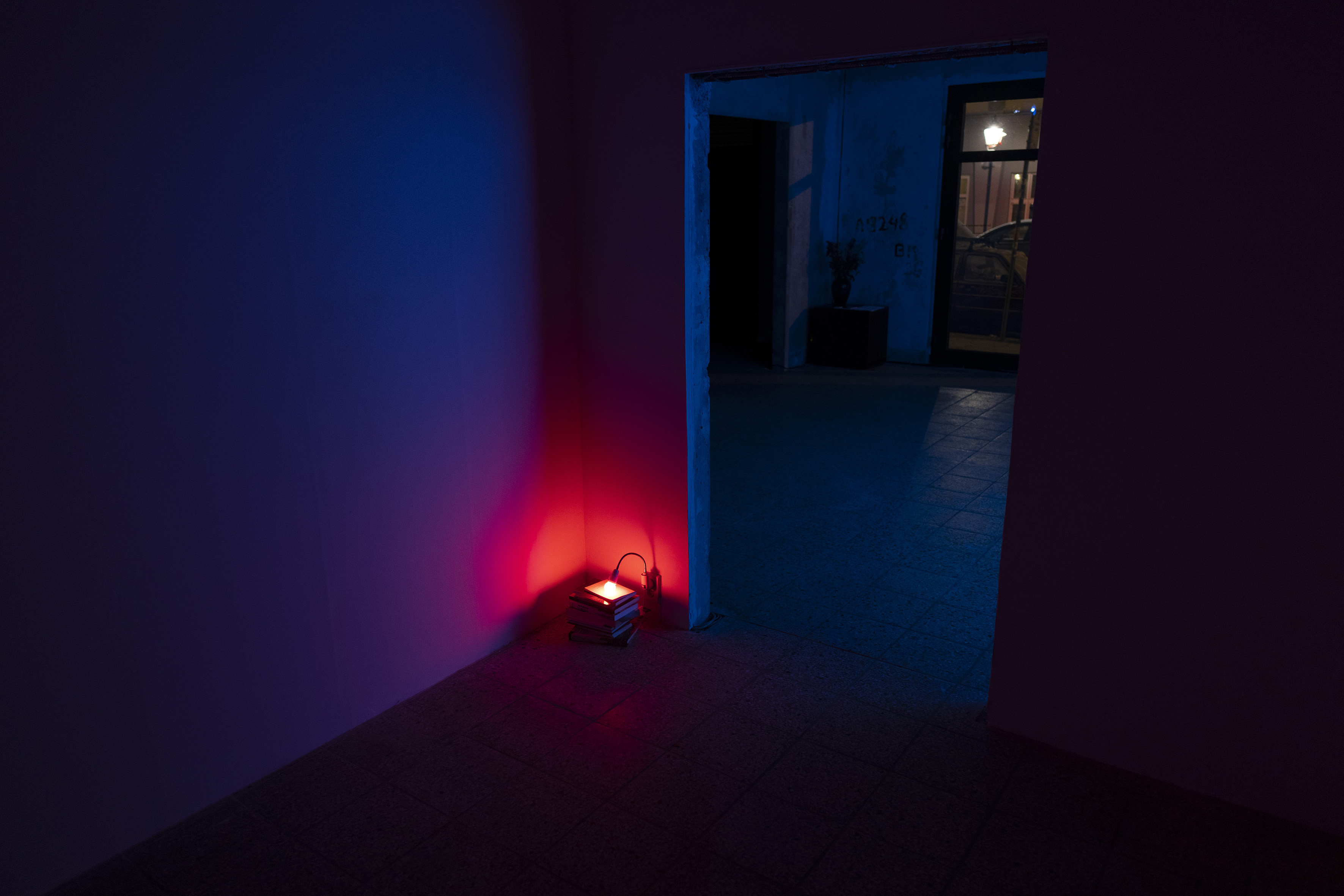 Lamplight Stack, red lamp, books, photograph, dimensions variable, 2023