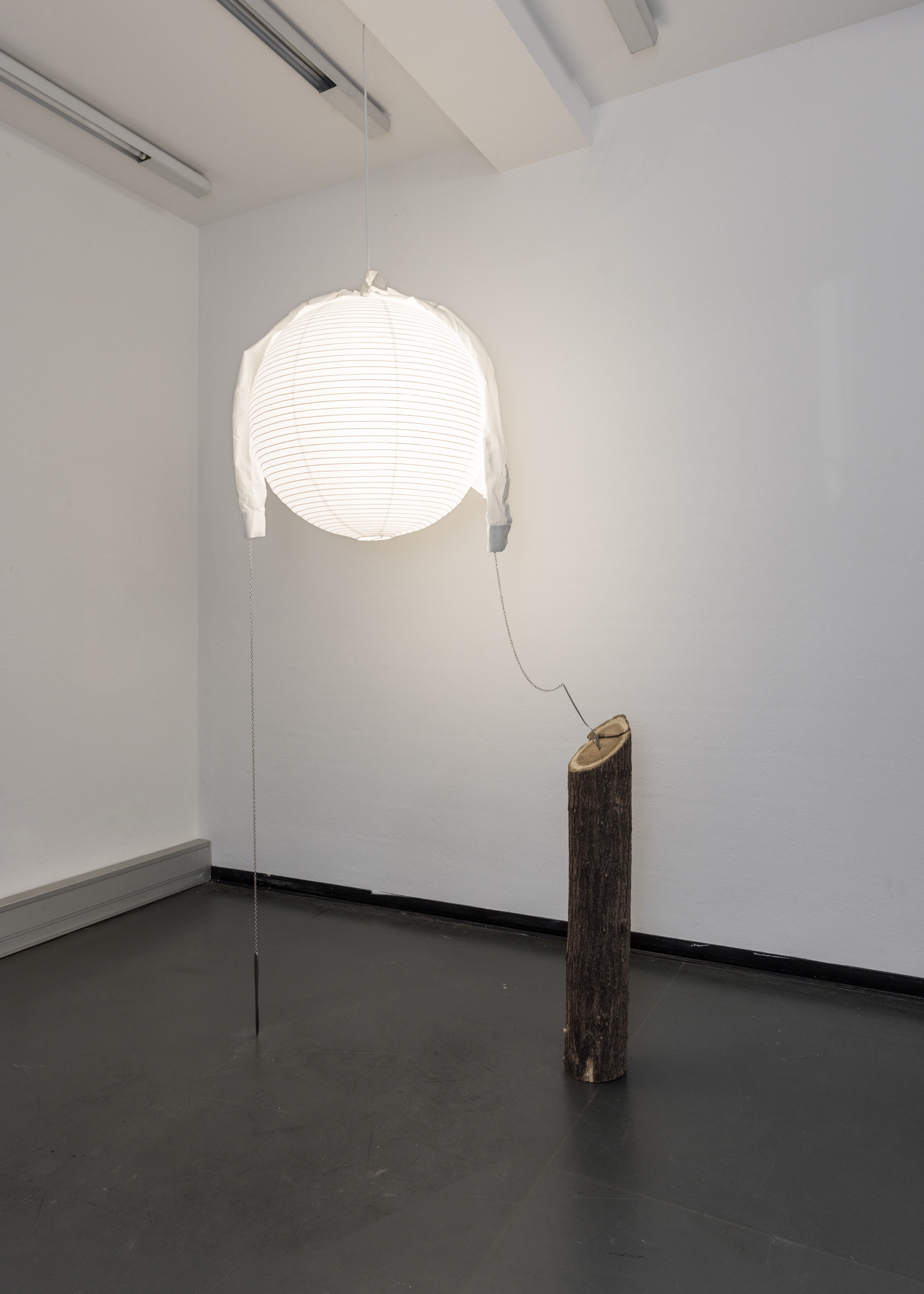 Mira Mann, imposter 2 (mercuryaristocrats), 2022. Paper lantern, light bulb, fork, knife, steel chain, locust trunk, shirt, 100 x 100 cm © 2024 nova space of Bauhaus-Universität Weimar, courtesy of the artist, photo: Jannis Uffrecht