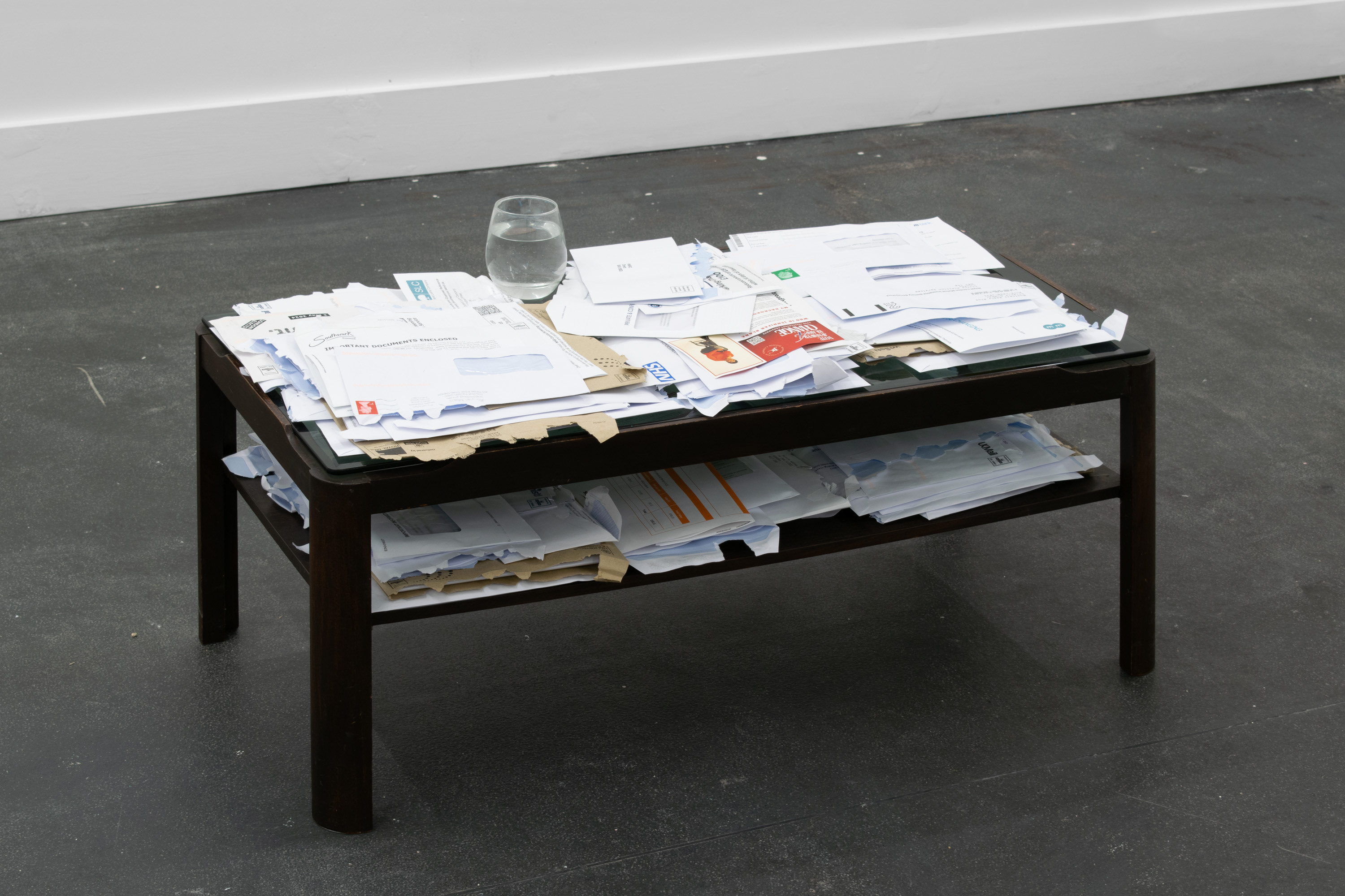Resting place, Hilda Kortei, Letters and envelopes, wooden coffee table, glass, water, 45 x 88 x 44 cm, 2024