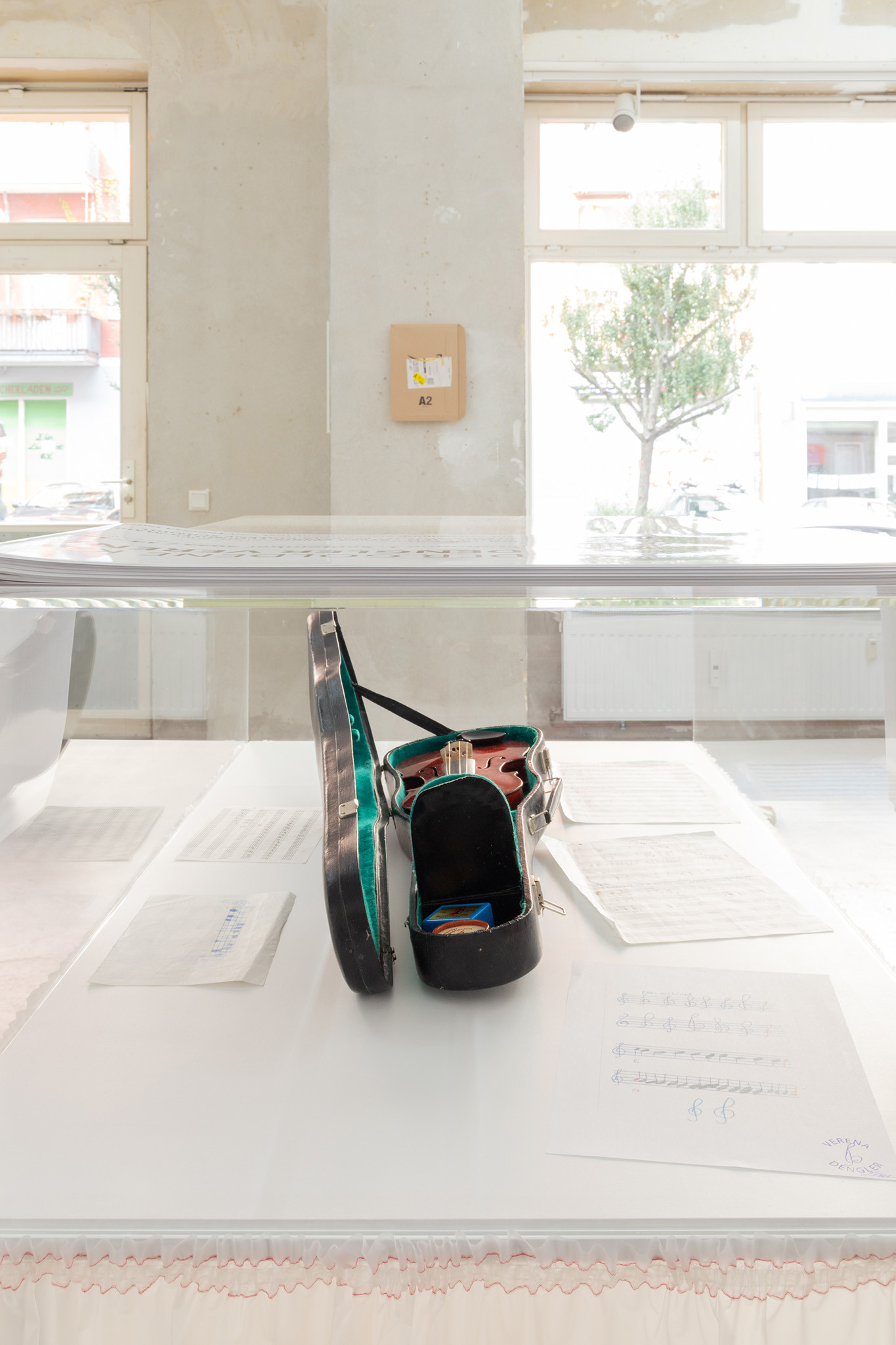 Verena Dengler, „Erste Geige”, sheet music composition Verena Dengler, early 1980s, sheet music, dimensions variable, violin in case with accessories, customized plate, plexiglass, plastic fabric, 111 x 122 x 71 cm, 2024