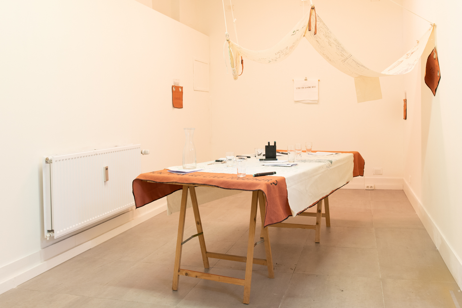 Angelina Nonaj, How can we live together?. 2024, Empty glasses, vinyl text, fabric, collective drawing, canvas